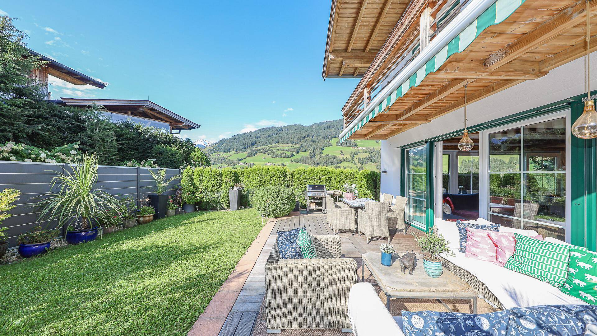 Sonnige Terrasse mit bequemen Loungemöbeln und Blick auf die umliegende Berglandschaft.