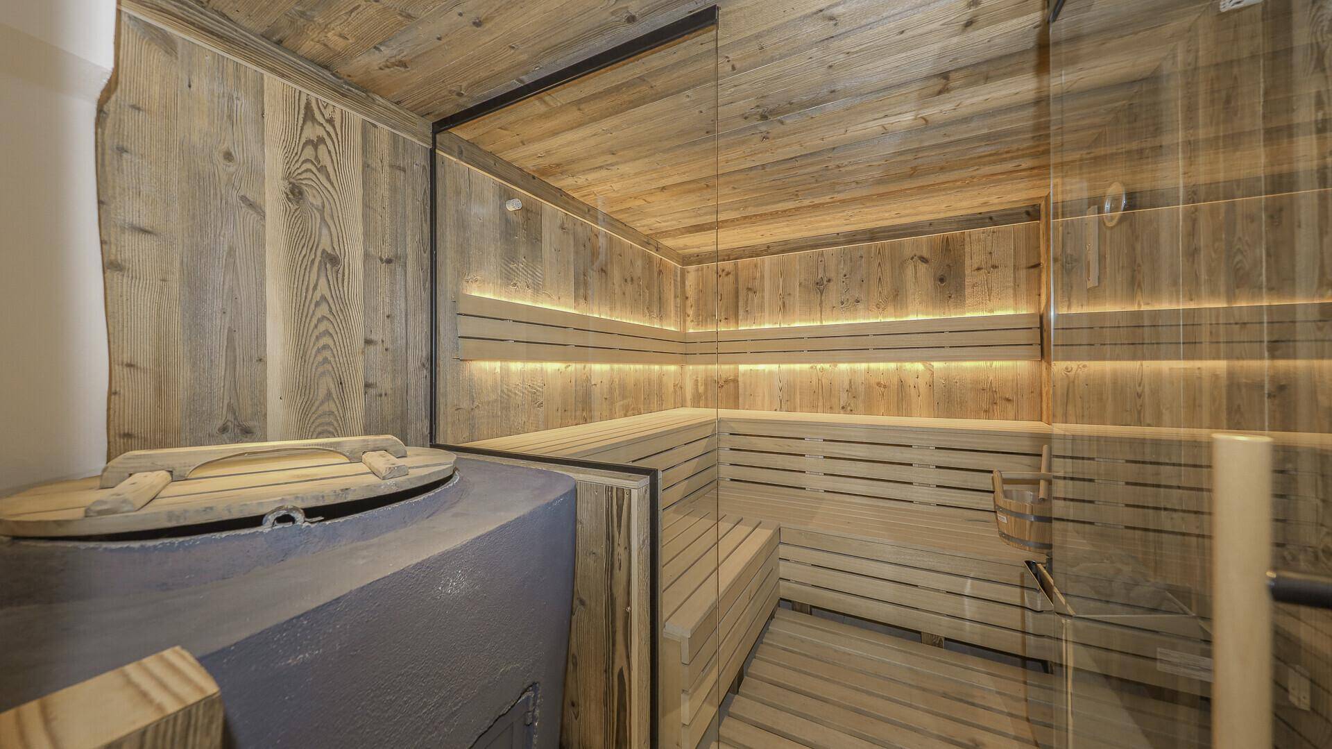 Moderne Sauna mit Holzbänken, indirekter Beleuchtung und Glasfront.