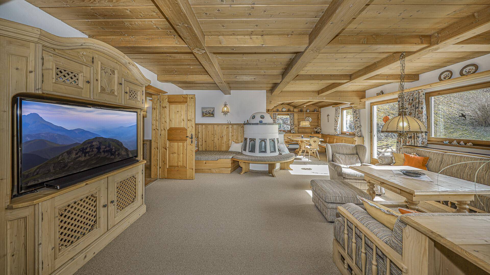 Gemütlicher Wohn- und Essbereich mit Kachelofen, Holzbalkendecke und traditioneller Einrichtung.