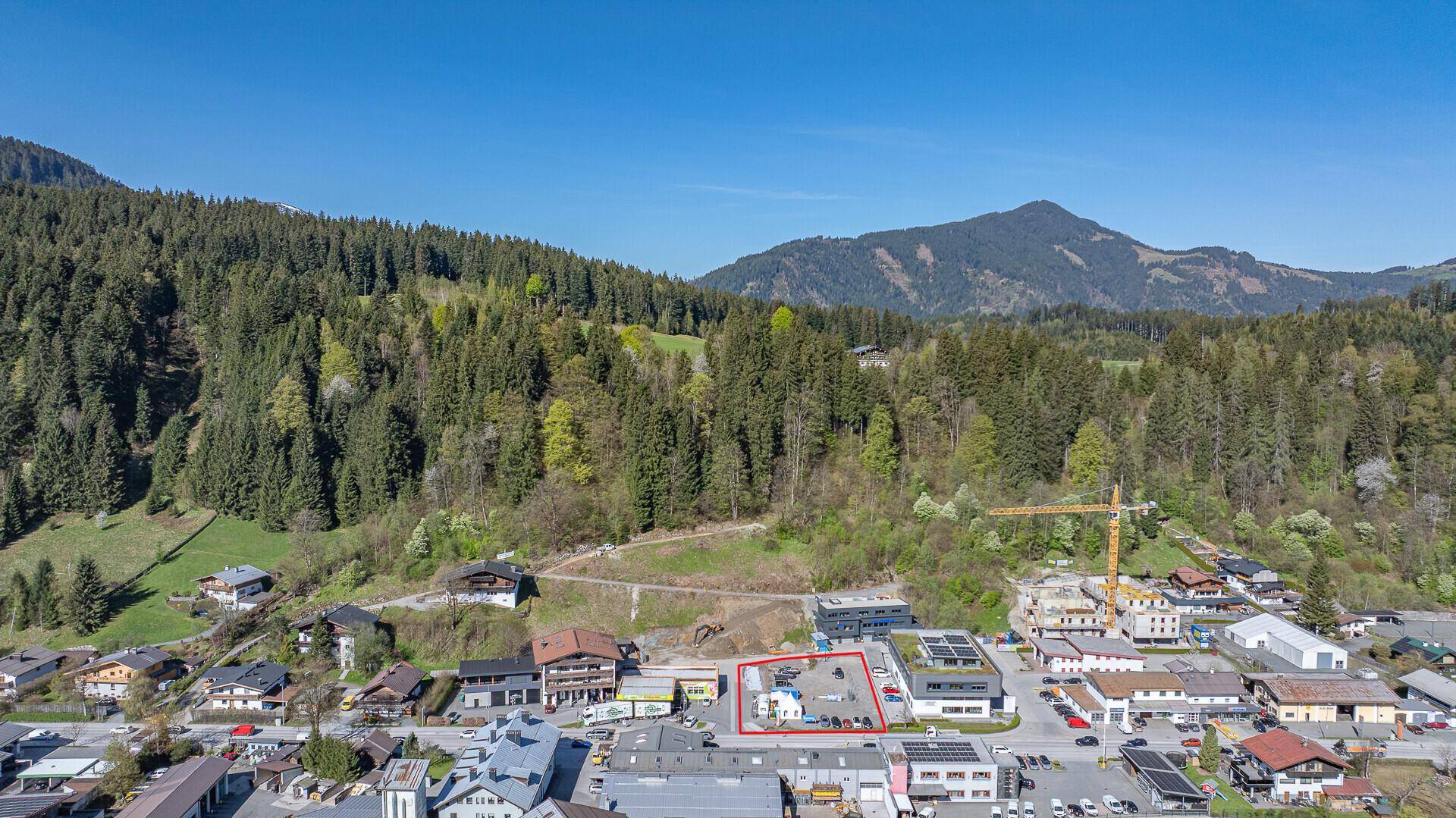 Weitläufige Luftaufnahme der Berglandschaft mit einem kleinen Dorf und dem markierten Grundstück.
