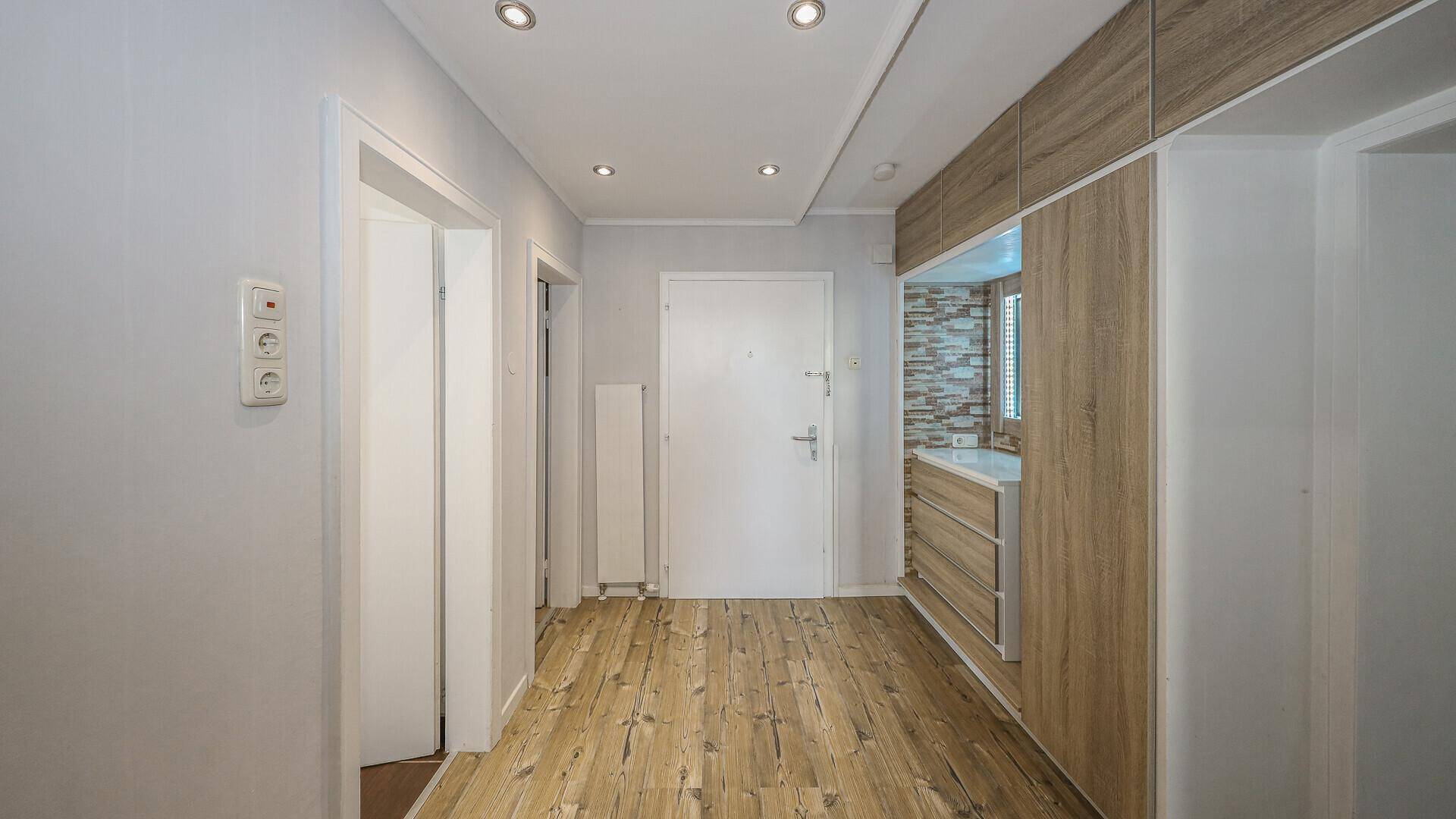 Heller Flur mit Holzboden, Einbauschränken und mehreren Türen, funktional gestaltet.