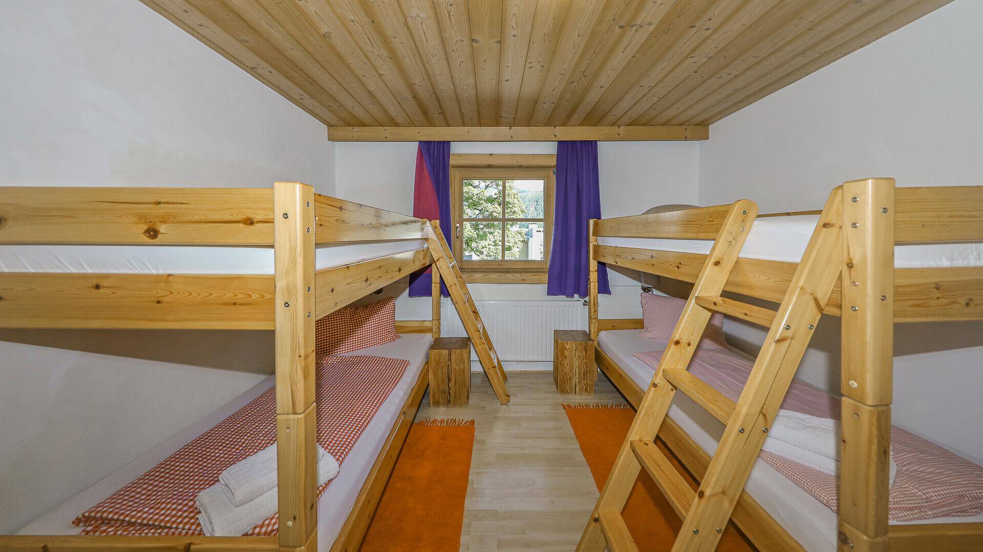 Kinderzimmer mit zwei Etagenbetten und Holzdecke, ideal für Familien.