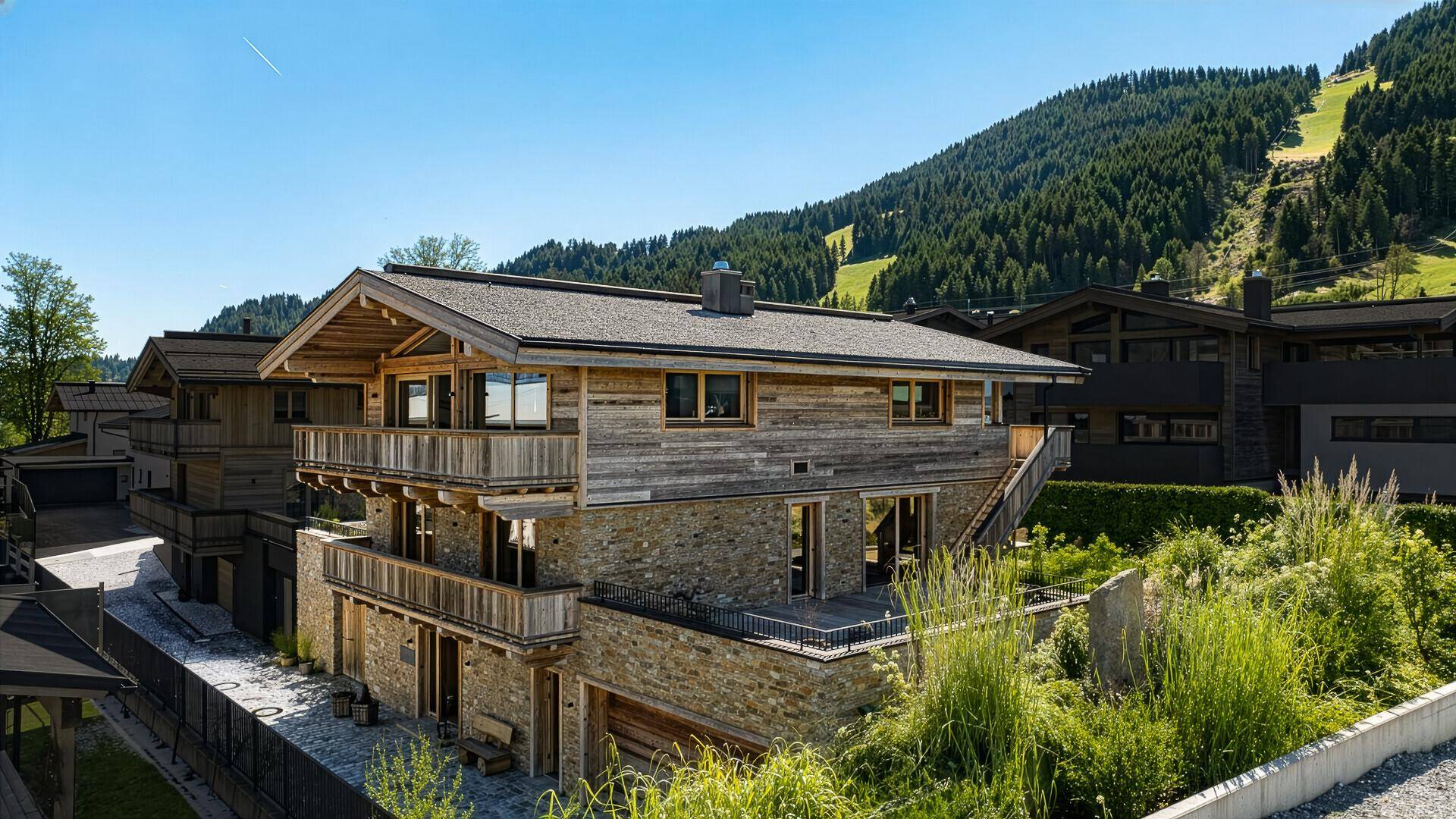 Alpines Holzhaus mit Steinfassade und Balkonen in einer malerischen Berglandschaft.