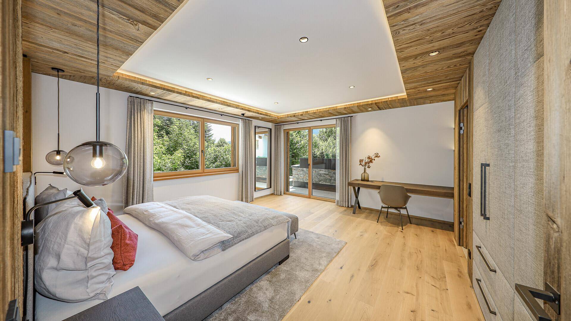 Helles Schlafzimmer mit Holzboden, Einbauschränken und Zugang zur Terrasse mit Gartenblick.