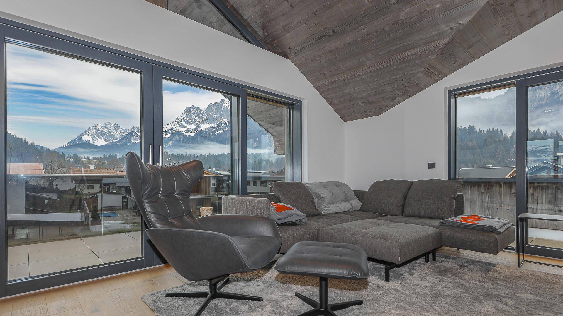 Gemütlicher Wohnbereich mit bequemen Sitzmöbeln und beeindruckendem Bergblick durch große Fenster.