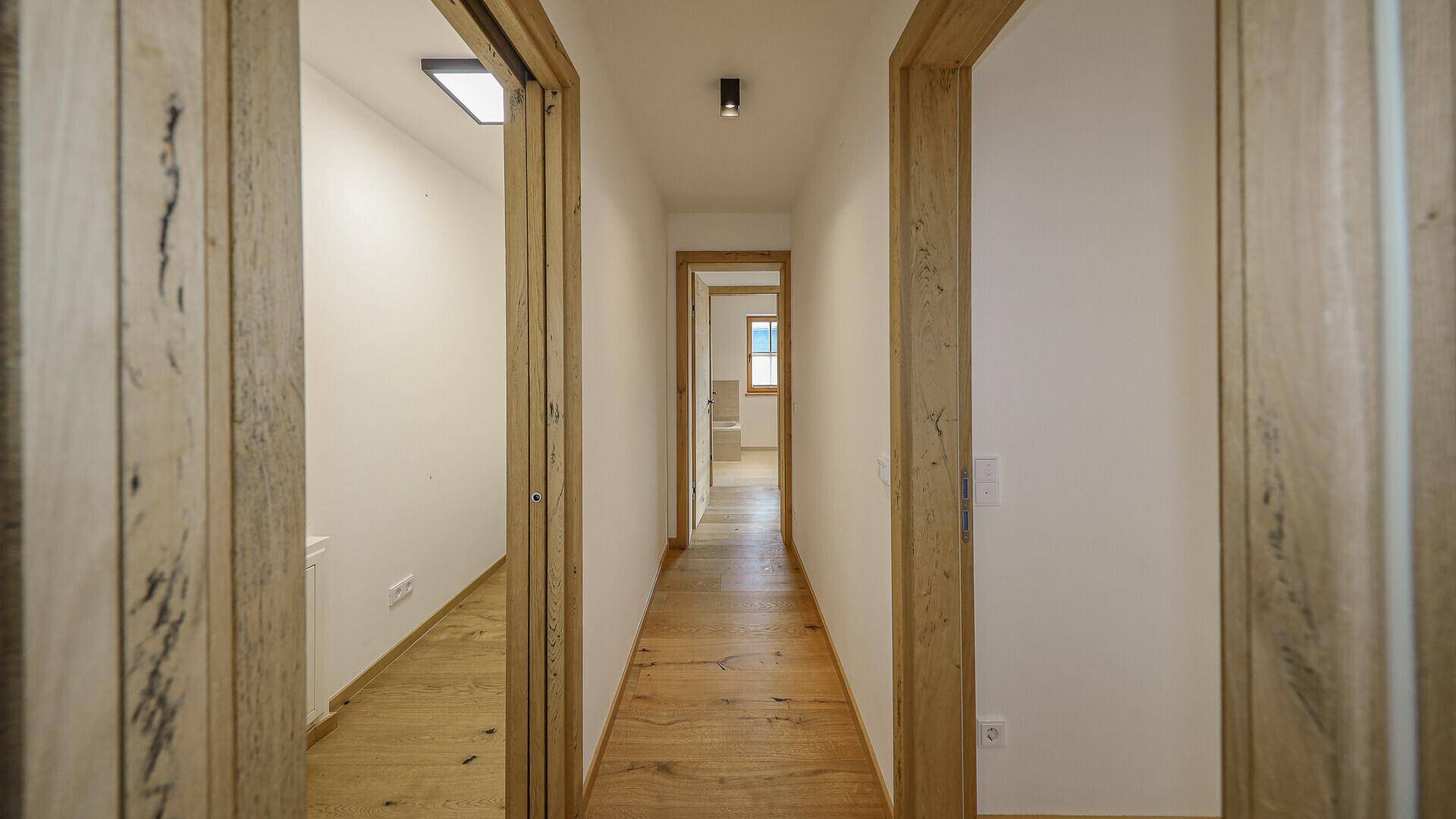 Heller Flur mit Holzboden und Holztüren, der zu weiteren Räumen führt.