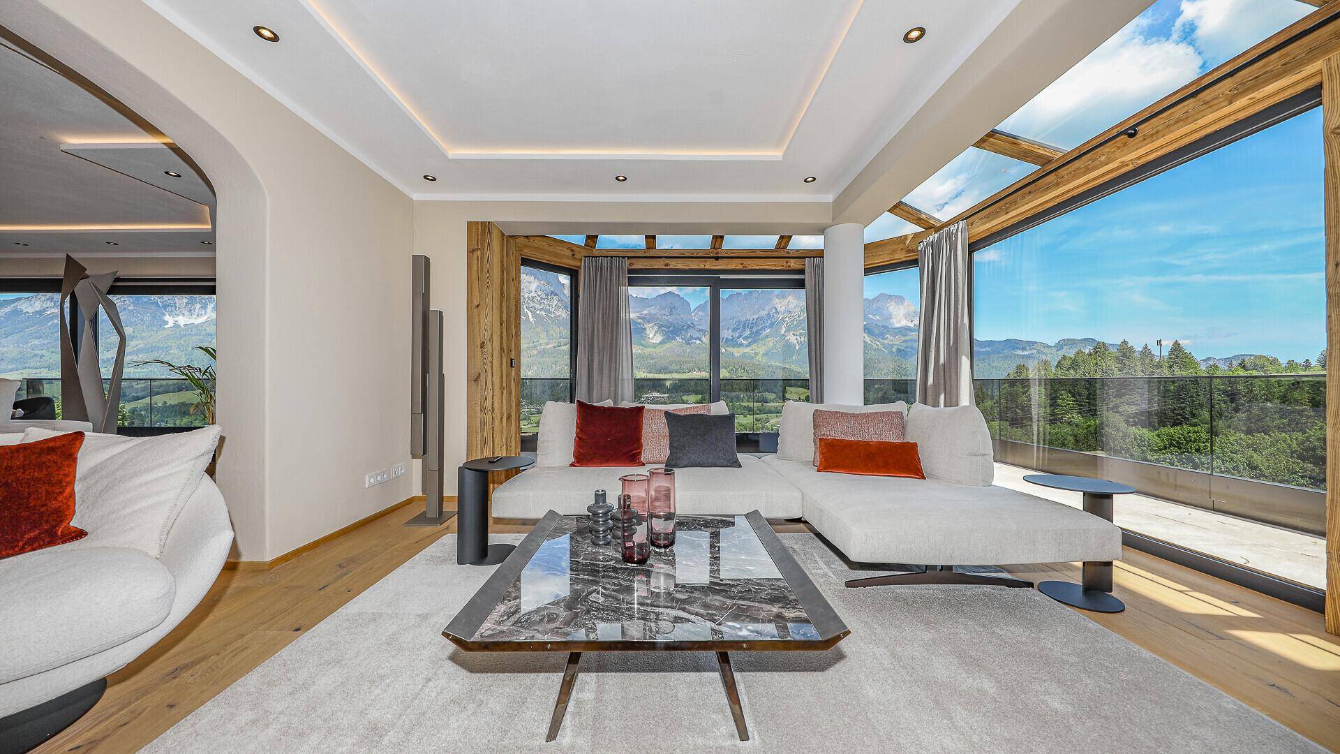 Helles Wohnzimmer mit Zugang zur Terrasse, Holzboden und weitem Blick auf die Berglandschaft.