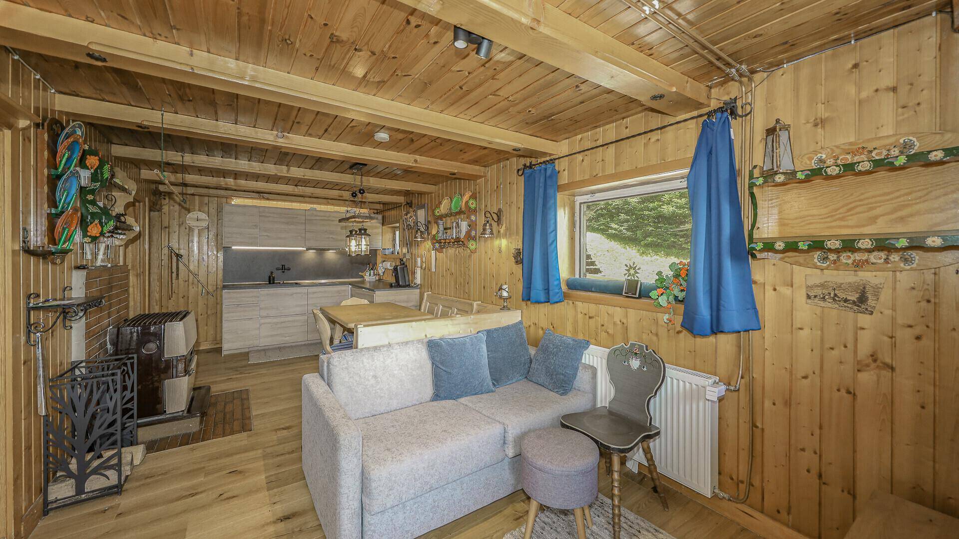 Heller Wohnbereich mit bequemer Couch, Holzwänden und Blick auf die moderne Küchenzeile.