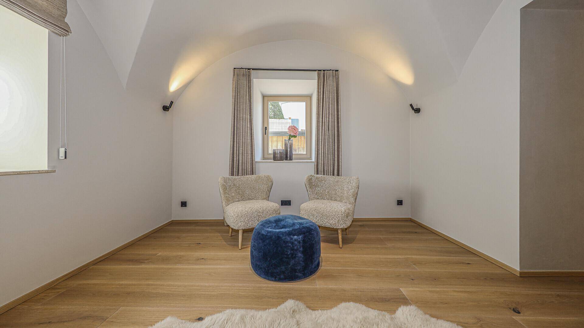 Geräumiges Schlafzimmer mit gewölbter Decke, Holzboden und Fenster mit Vorhängen.