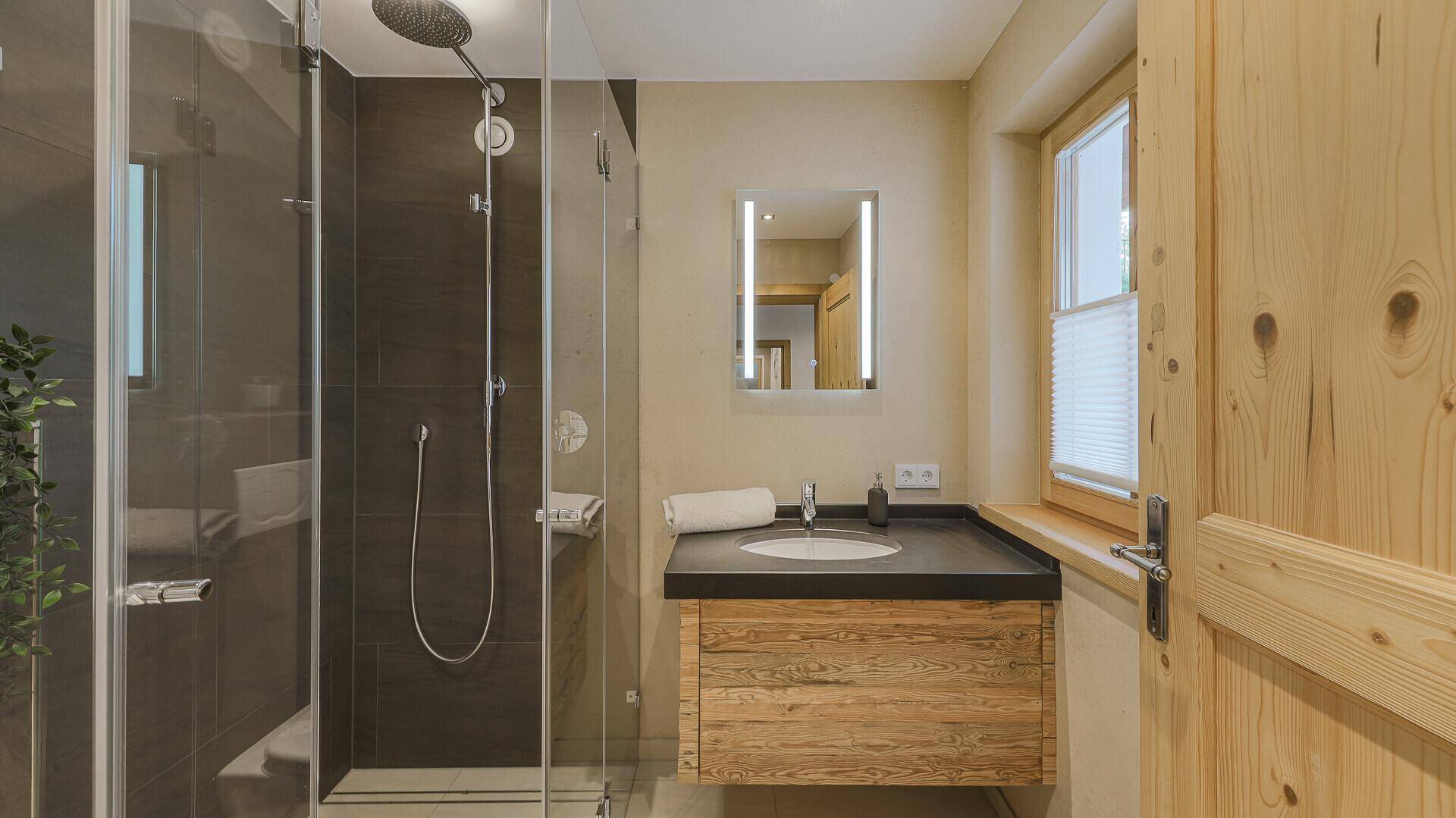 Helles Badezimmer mit Einzelwaschbecken, begehbarer Dusche und Fenster für Tageslicht.
