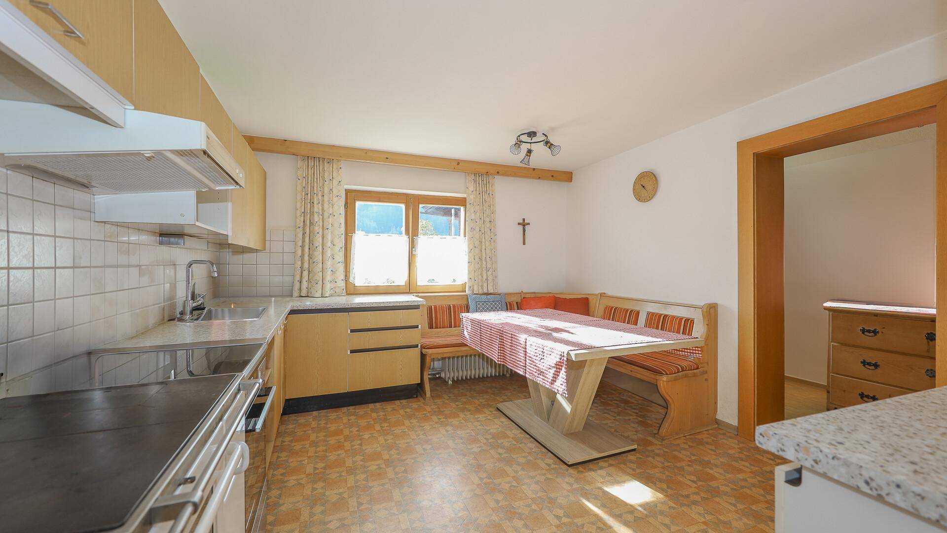 Traditionelle Küche mit Essbereich, Holzmöbeln und einem Fenster mit Blick ins Grüne.