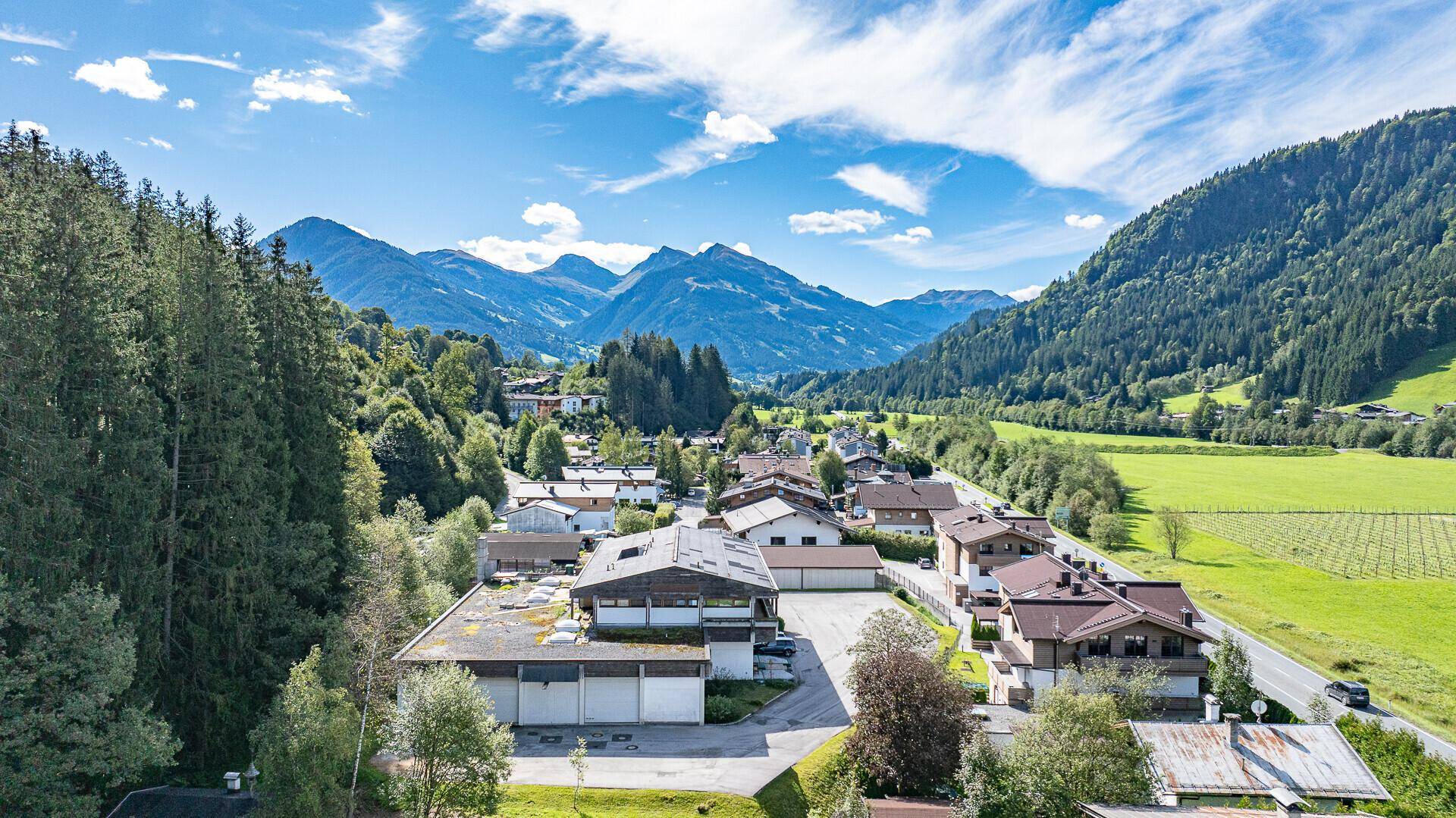 Weitläufige Luftaufnahme des Anwesens in einer idyllischen Berglandschaft mit viel Grün und klarem Himmel.