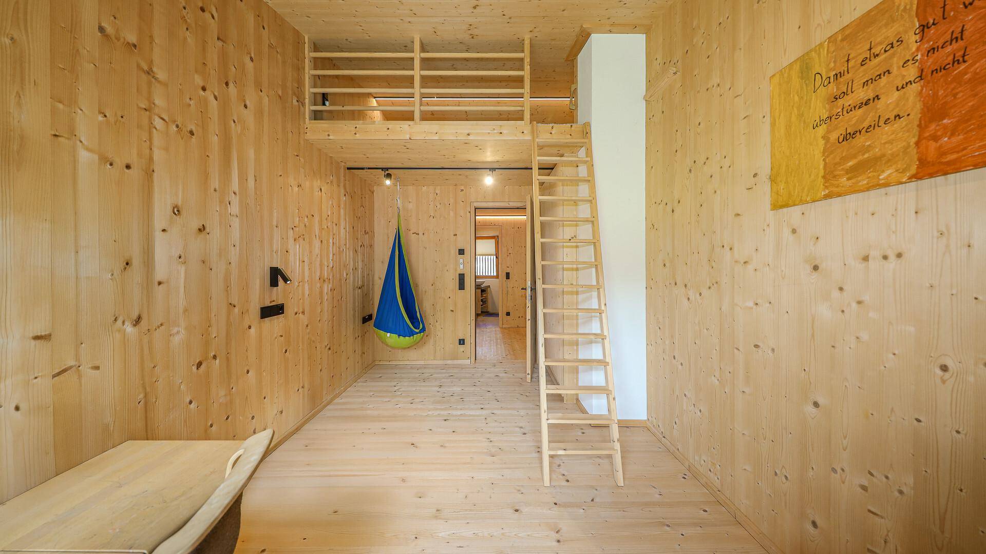 Vielseitiges Zimmer mit Holzwänden, Schreibtisch und Hochbett, bietet Raum für Kreativität und Entspannung.