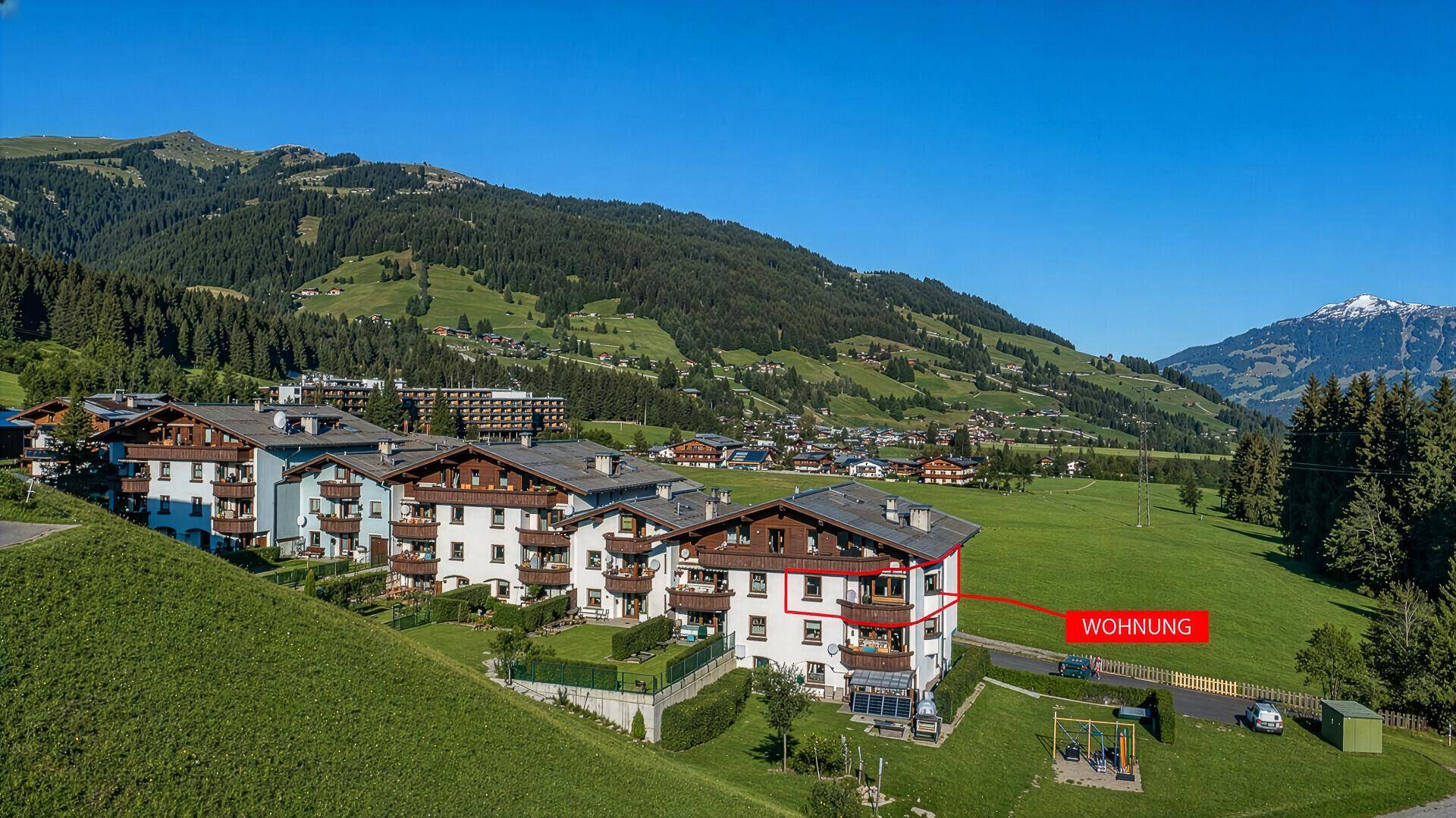 Luftaufnahme einer Wohnanlage in den Bergen mit Blick auf die grüne Umgebung.