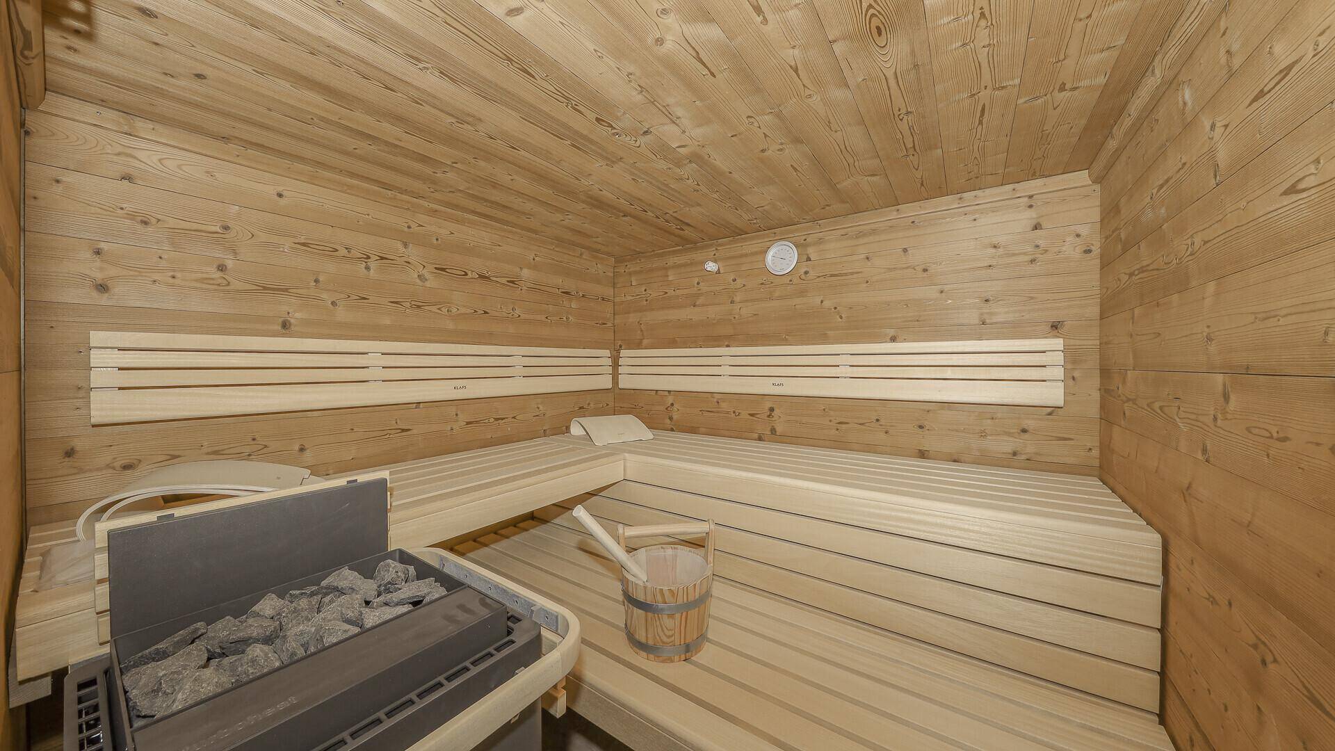 Traditionelle Holzsauna mit Bänken und Saunaofen für entspannende Momente.