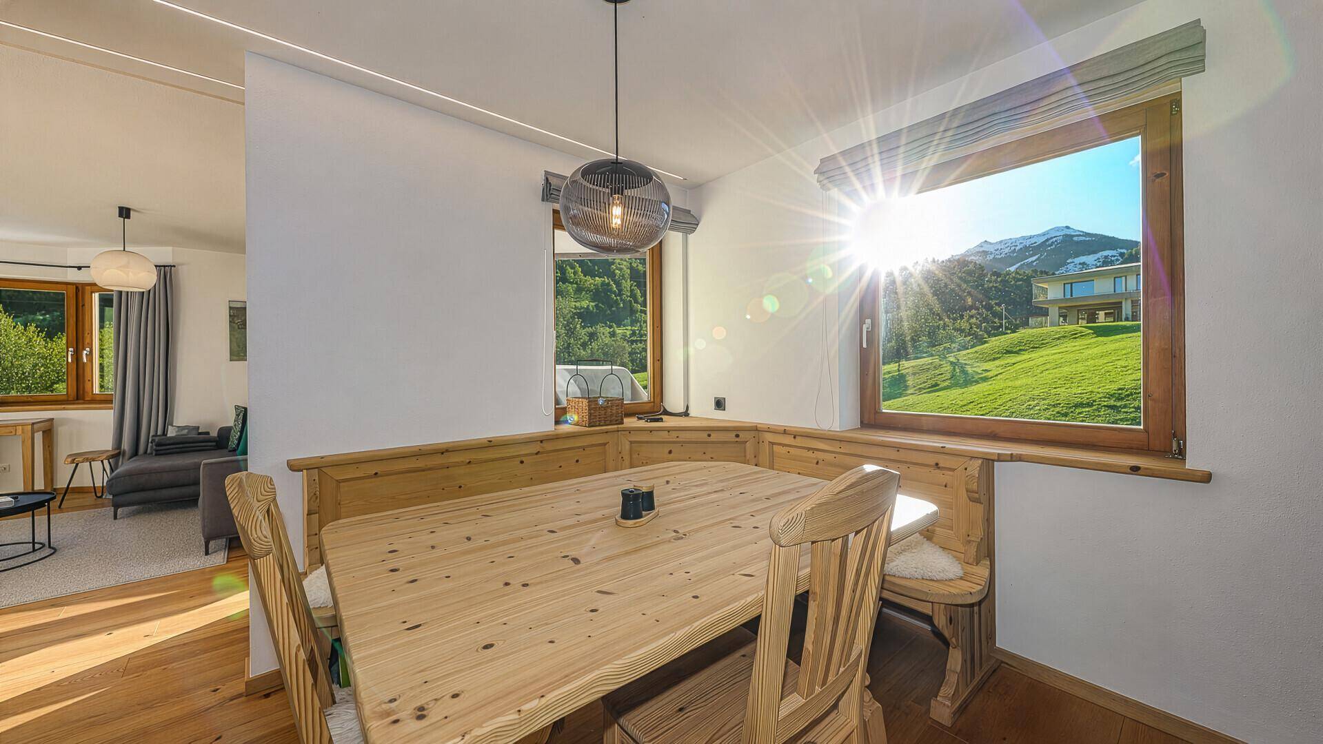 Gemütlicher Essbereich mit Holztisch und Sitzbank, lichtdurchflutet mit Bergblick.