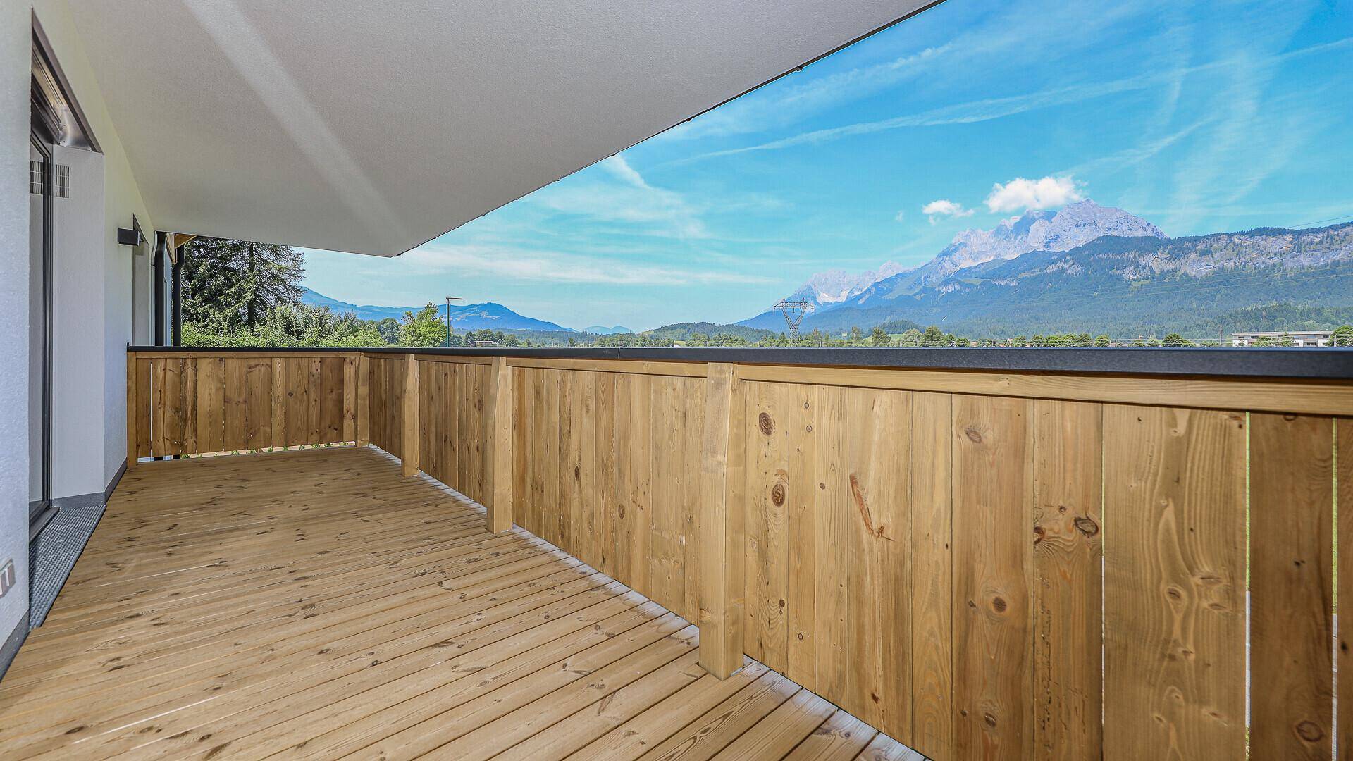 Überdachter Balkon mit Holzboden und Holzgeländer, ideal für entspannte Stunden mit Bergblick.