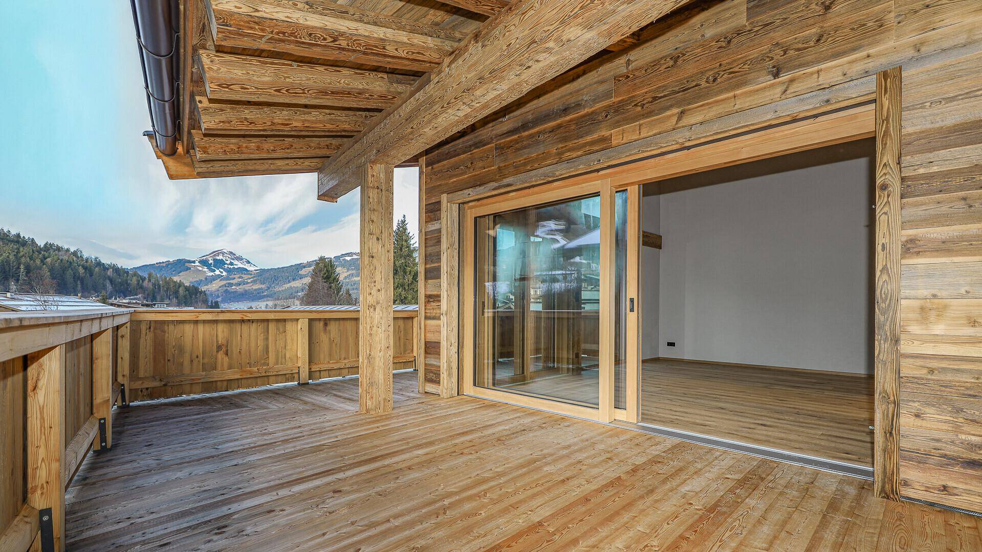 Geräumiger Holzbalkon mit Schiebetüren zum Innenbereich und weitem Bergblick.