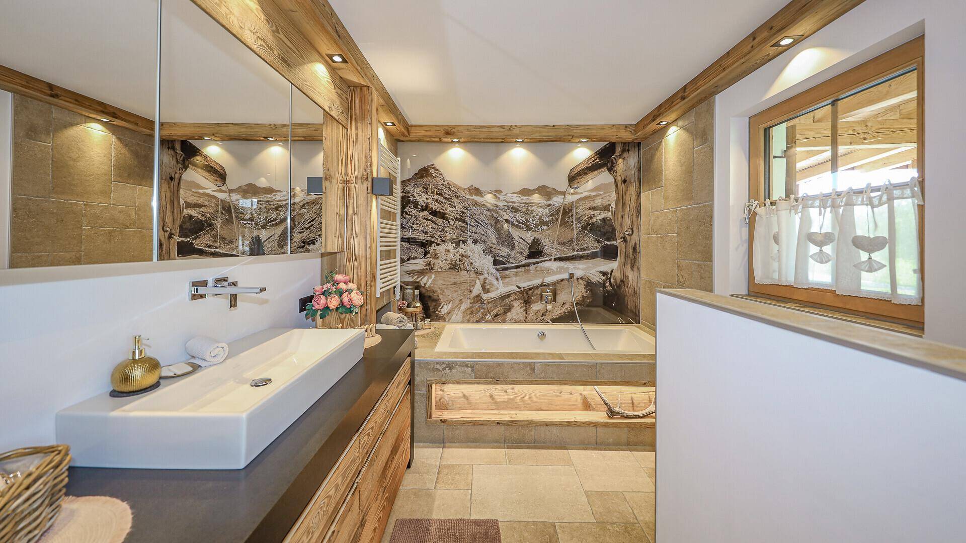 Modernes Badezimmer mit Doppelwaschbecken, Badewanne und alpiner Wandgestaltung.