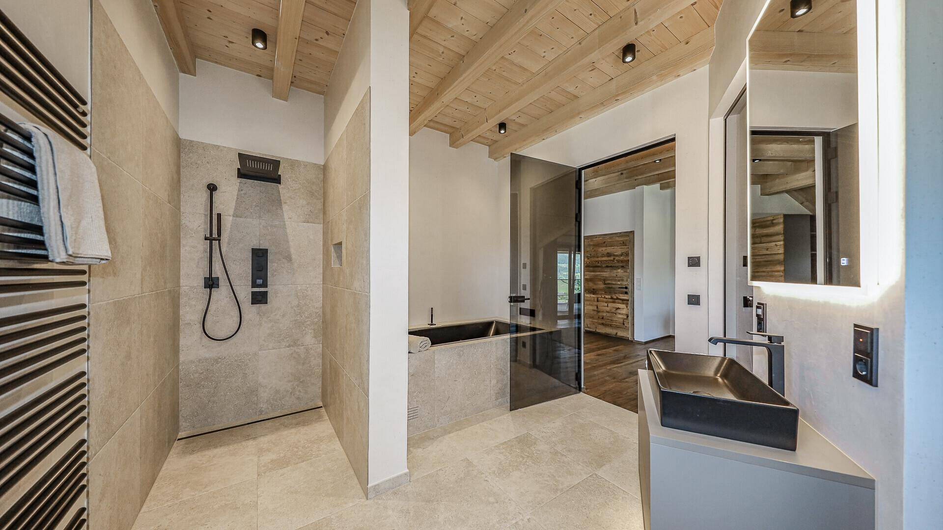 Modernes Badezimmer mit begehbarer Dusche, stilvollem Waschbecken und Holzbalkendecke.