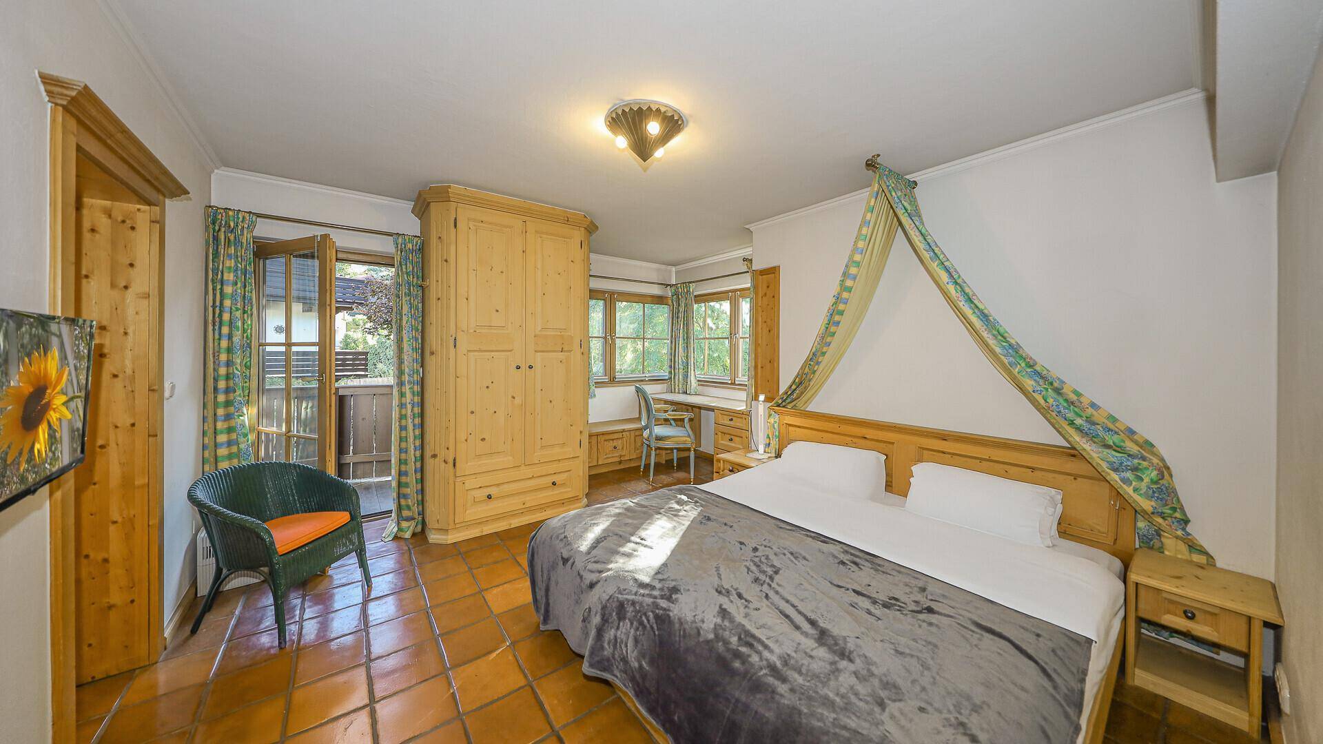 Helles Schlafzimmer mit Doppelbett, Terrakottafliesen und Zugang zum Balkon.
