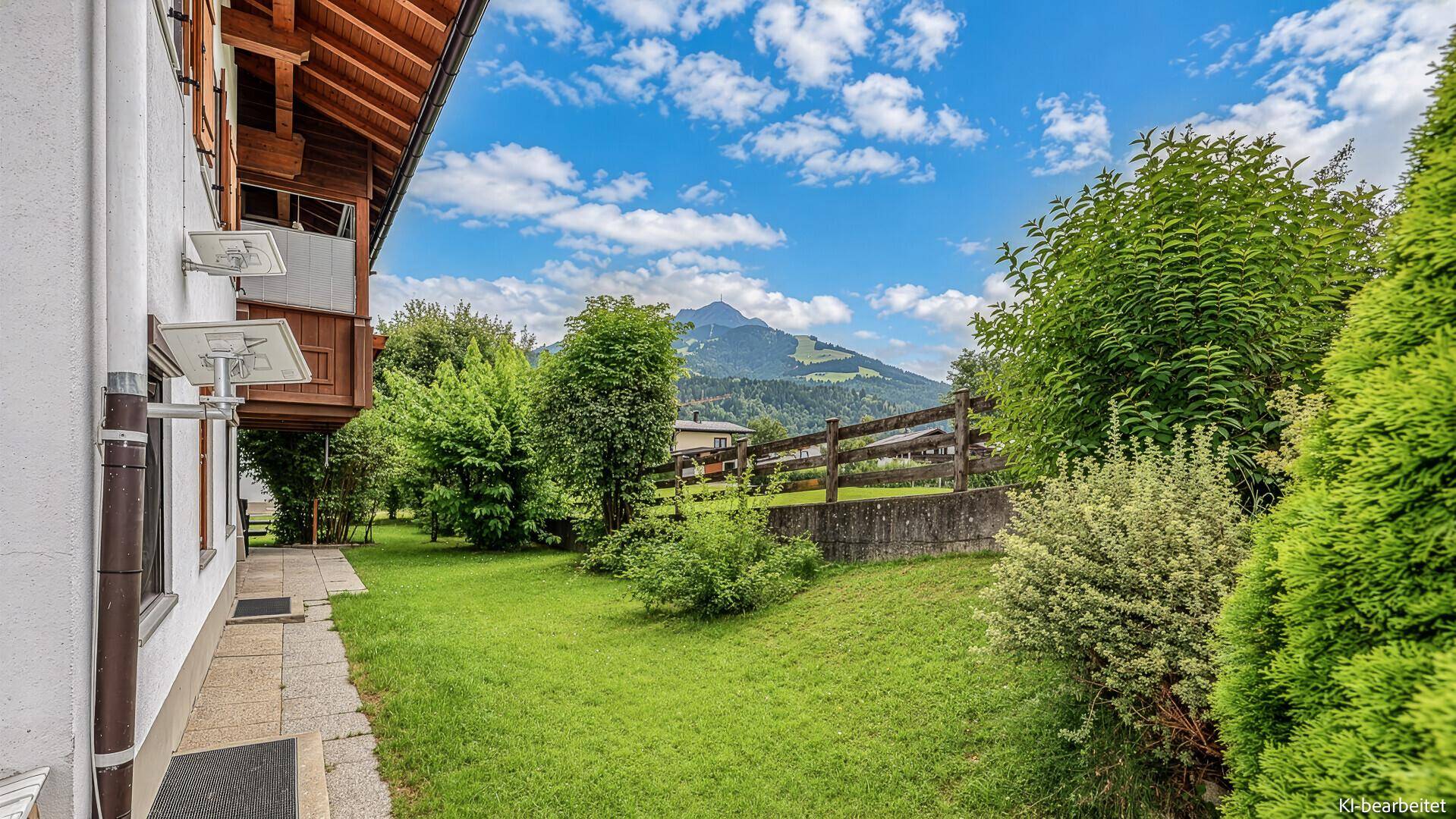 Gepflegter Gartenbereich mit Rasenfläche und einem malerischen Blick auf die umliegenden Berge.
