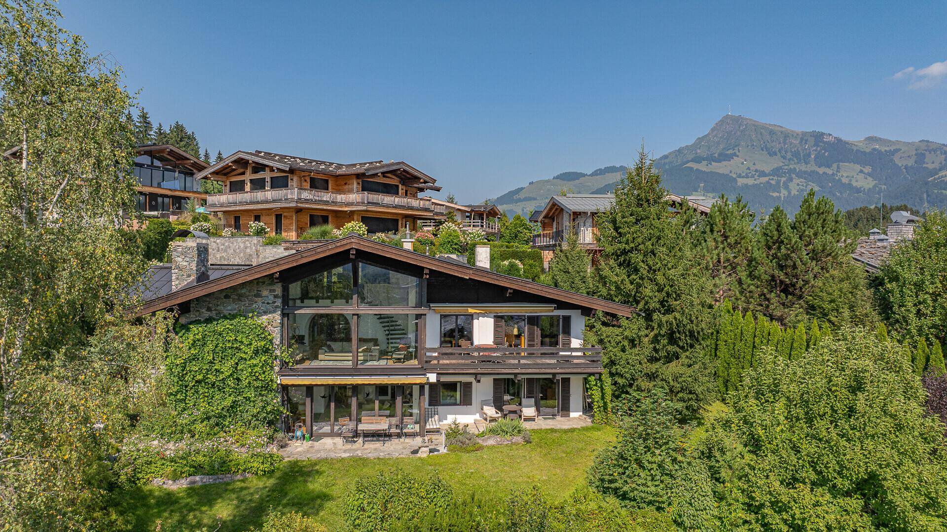 Großzügiges Anwesen in den Bergen mit traditioneller Stein- und Holzfassade und weitem Blick.
