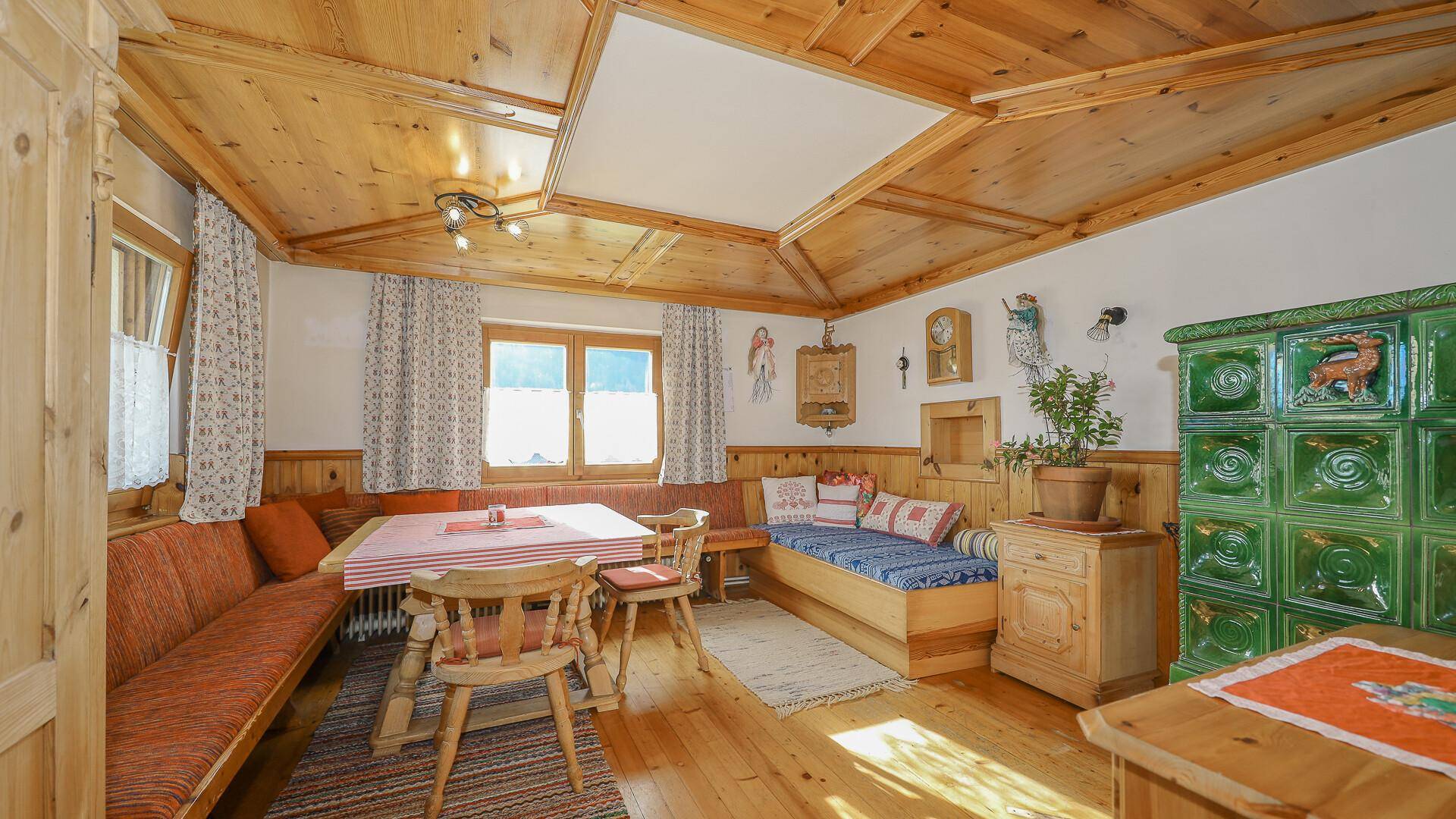 Gemütlicher Essbereich im alpinen Stil mit Holztäfelung, Kachelofen und traditionellen Sitzbänken.