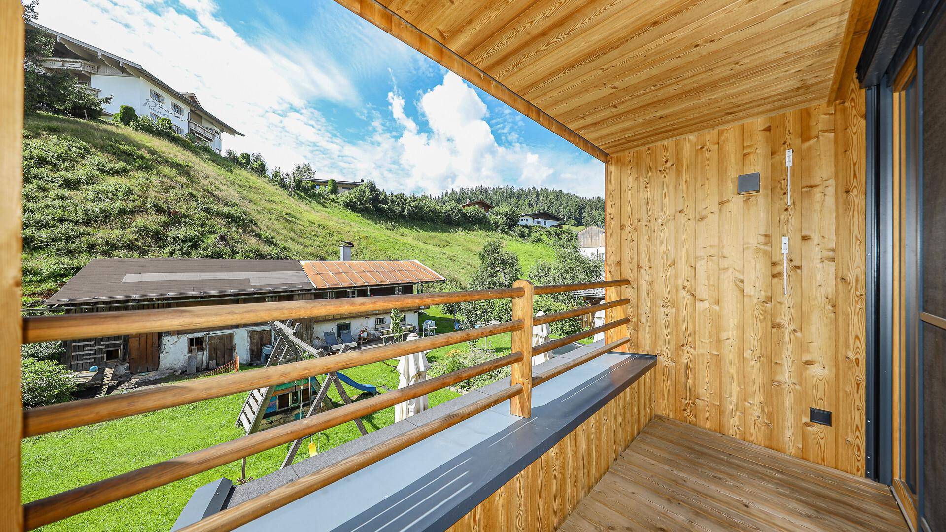 Kleiner Holzbalkon mit Geländer und weitem Blick auf die grüne Hügellandschaft.