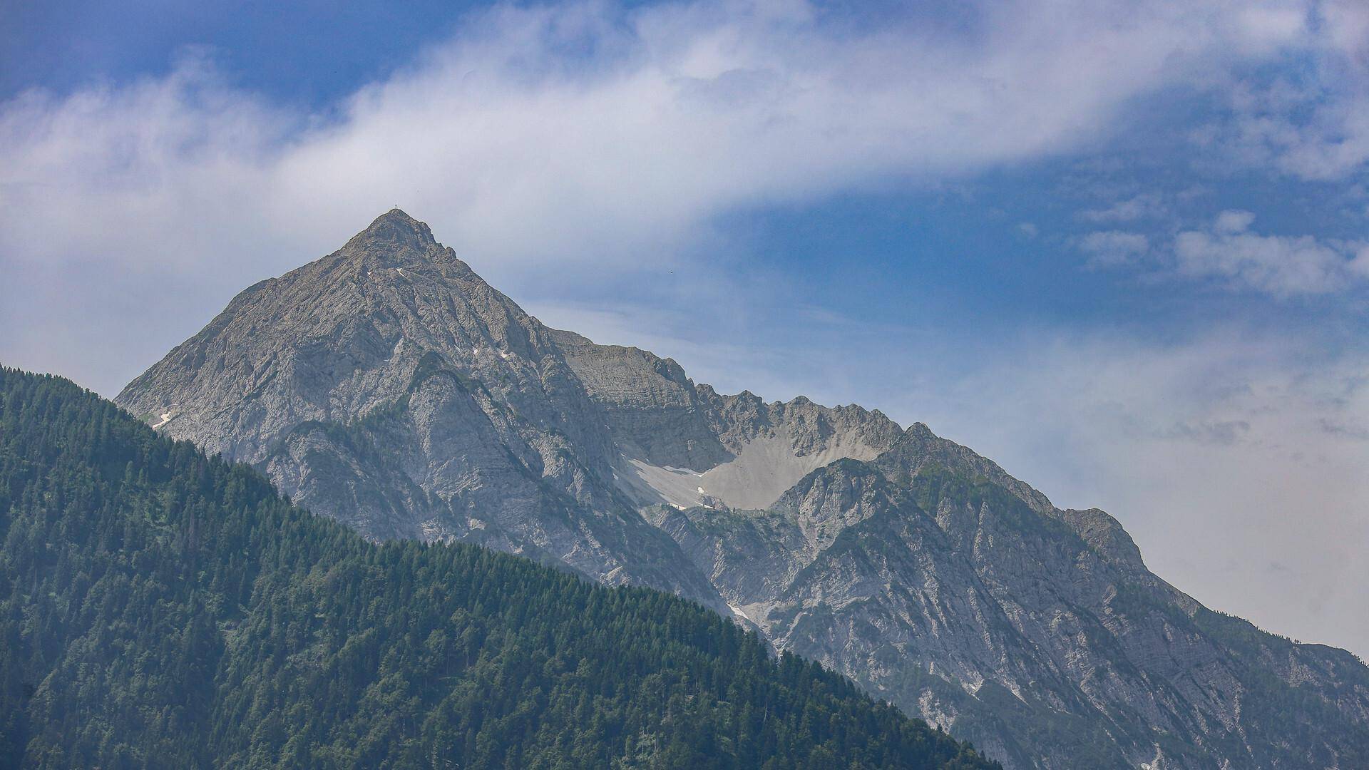 Detailansicht eines zerklüfteten Berggipfels, der sich majestätisch über die Baumgrenze erhebt.