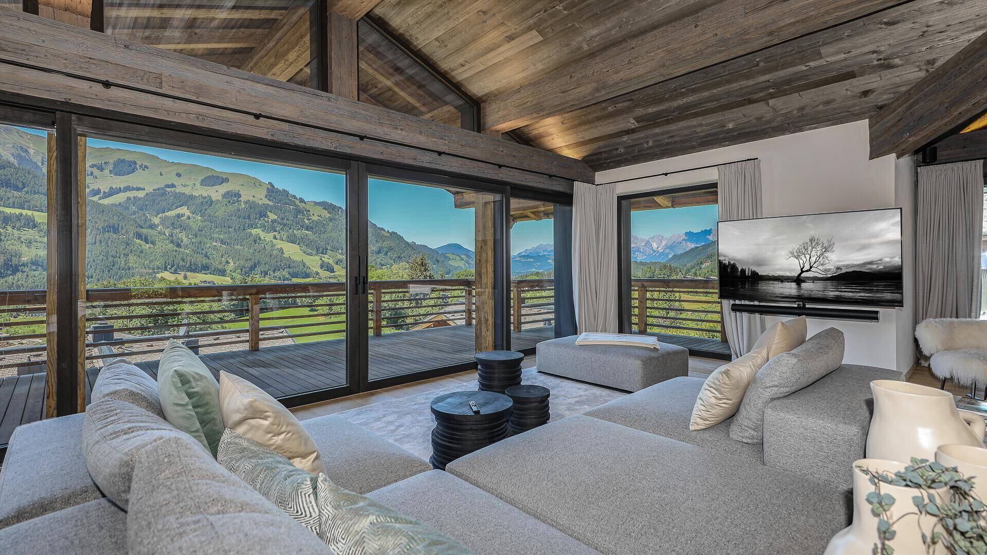 Helles Wohnzimmer mit großen Fenstern, die einen weiten Blick auf die Berge und die Natur bieten.