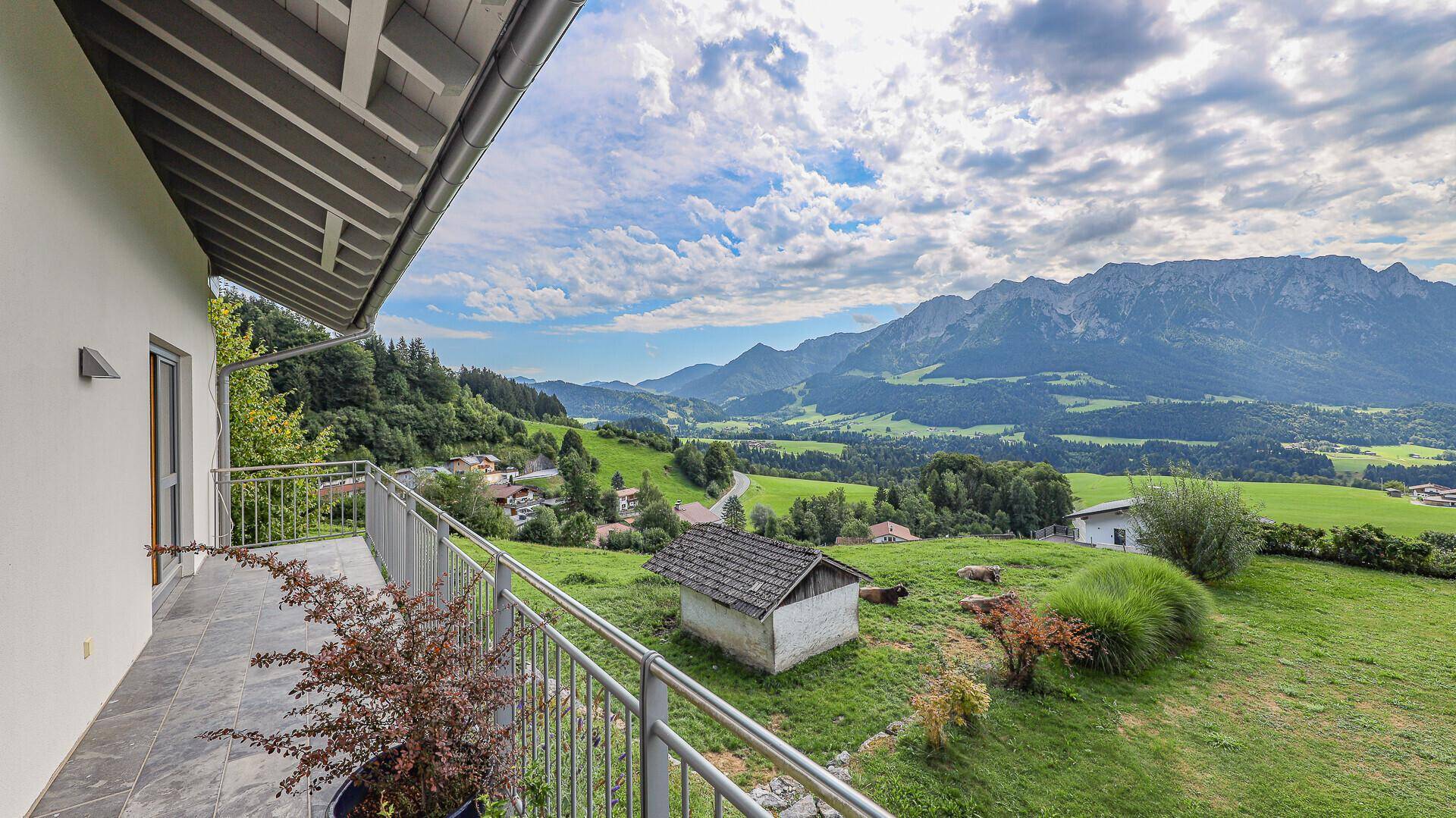 Balkon mit Panoramablick auf die umliegende Bergwelt und die weitläufige grüne Landschaft.