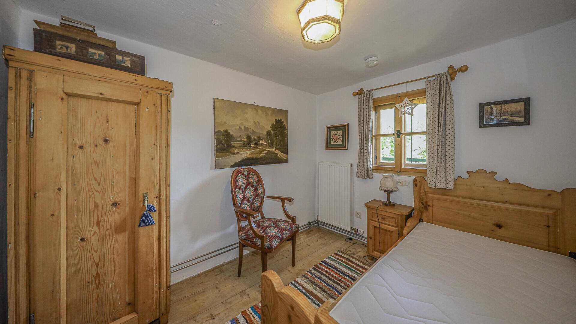 Schlafzimmer im Originalzustand mit Einzelbett, Holzschrank und rustikalen Details.