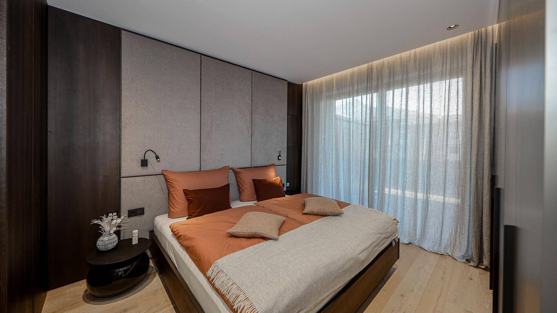 Gemütliches Schlafzimmer mit Holzakzenten, großem Bett und indirekter Beleuchtung.