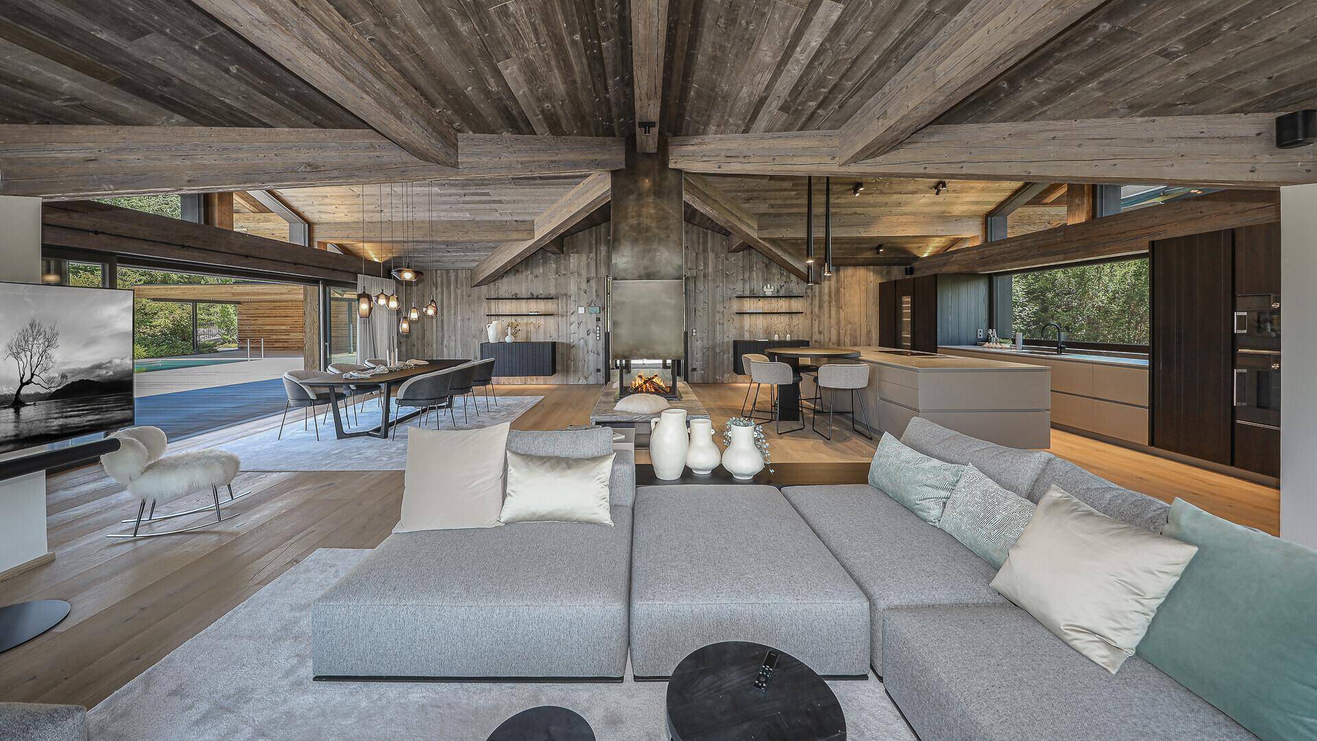 Großzügiges Wohnzimmer mit bequemer Sofalandschaft, Kamin und offener Gestaltung zur Küche.