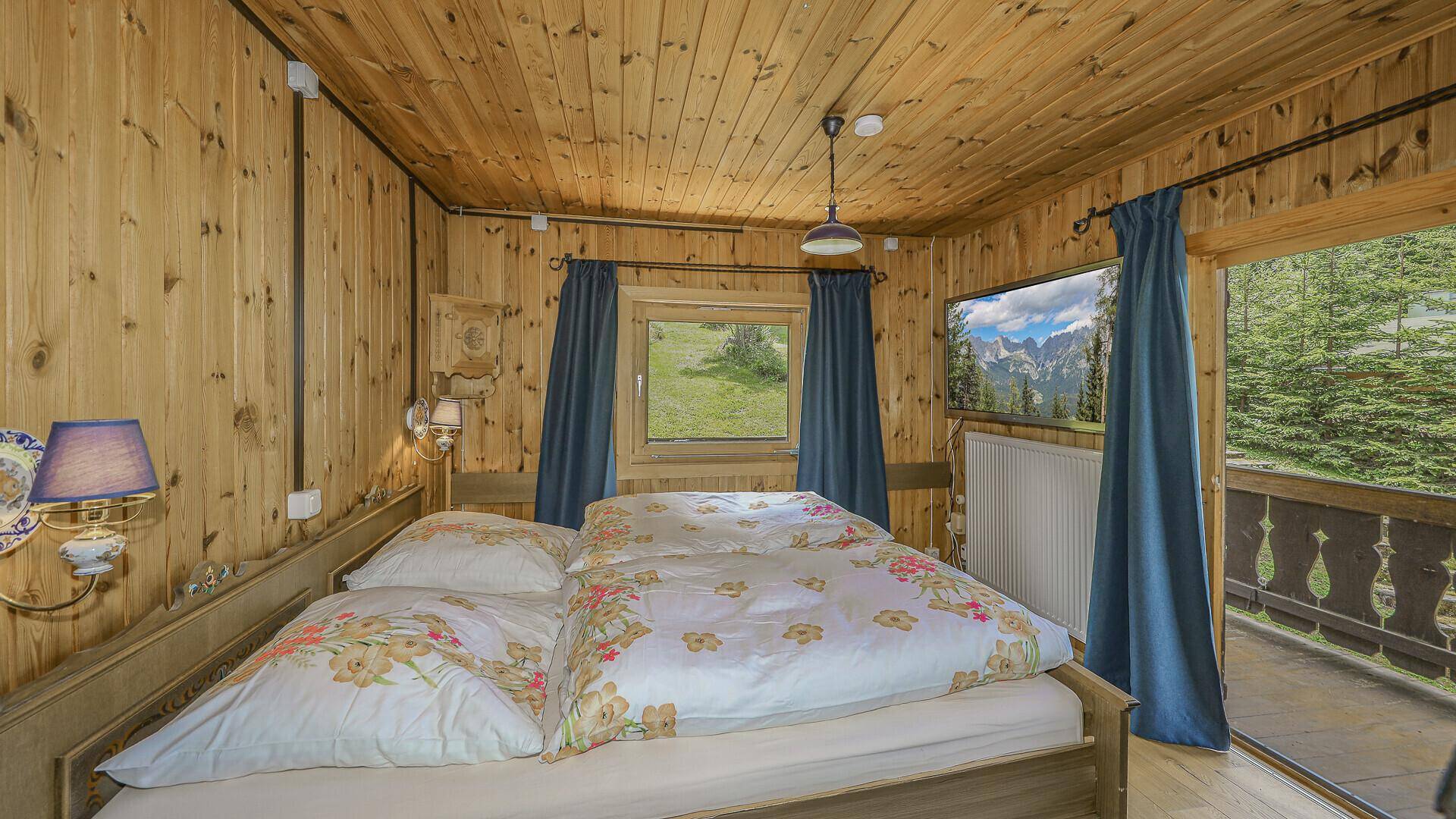 Schlafzimmer mit Doppelbett, Fenster und direktem Zugang zum Balkon, bietet frische Bergluft.