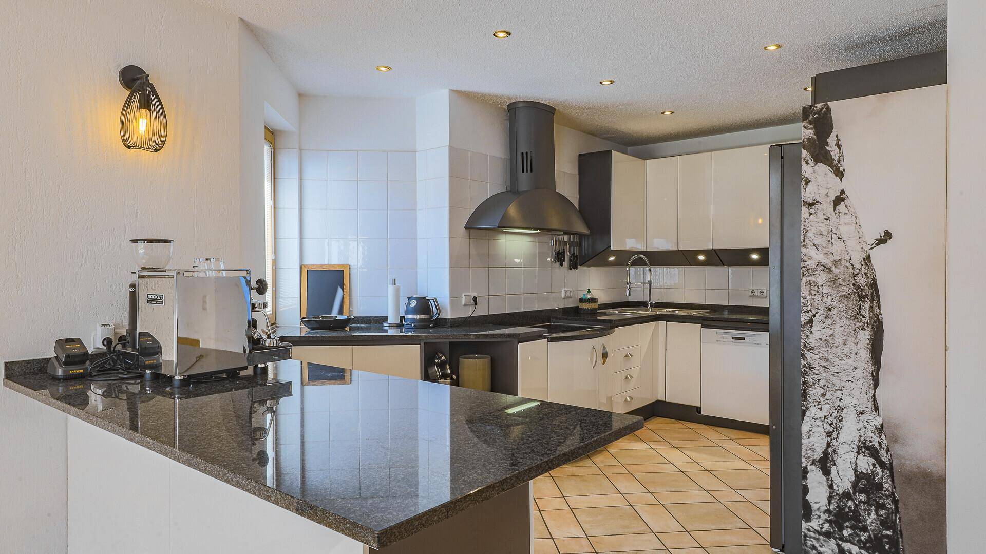 Moderne Küche mit weißen Schränken, dunklen Granitarbeitsplatten und integrierten Geräten.