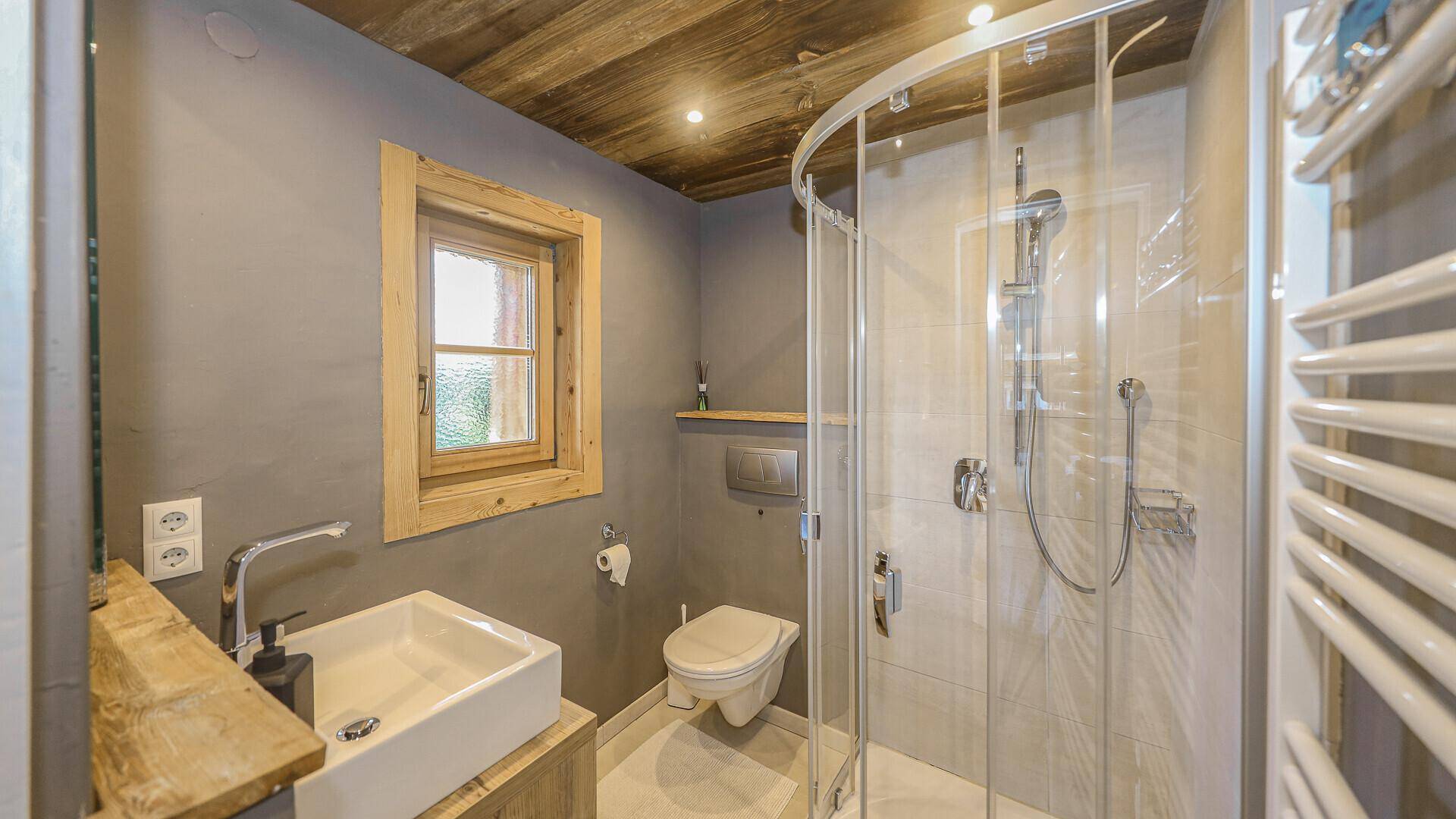 Modernes Badezimmer mit Dusche, Waschbecken und Holzdecke.