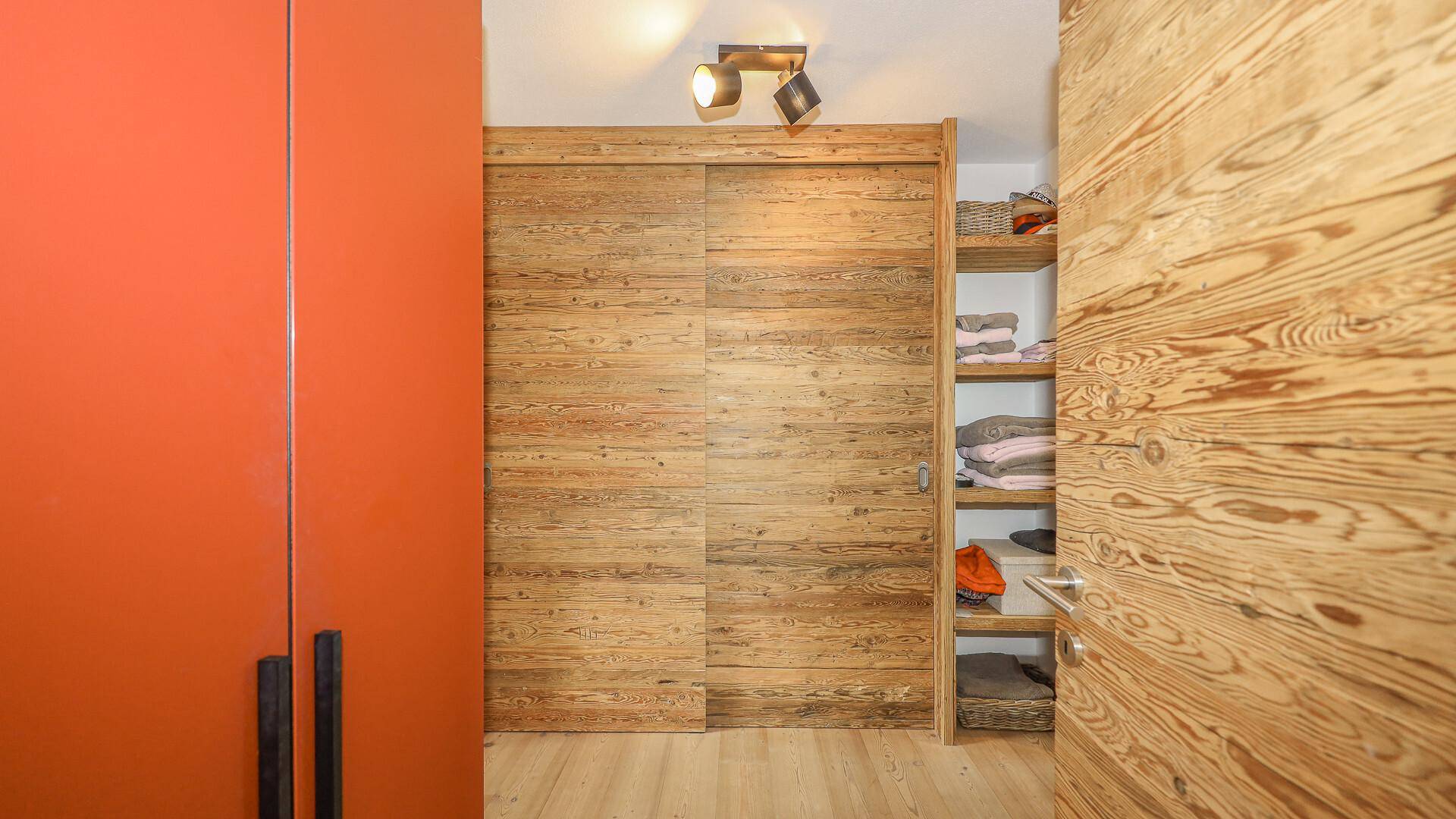 Begehbarer Kleiderschrank mit Holzschiebetüren und integrierten Regalen für Stauraum.