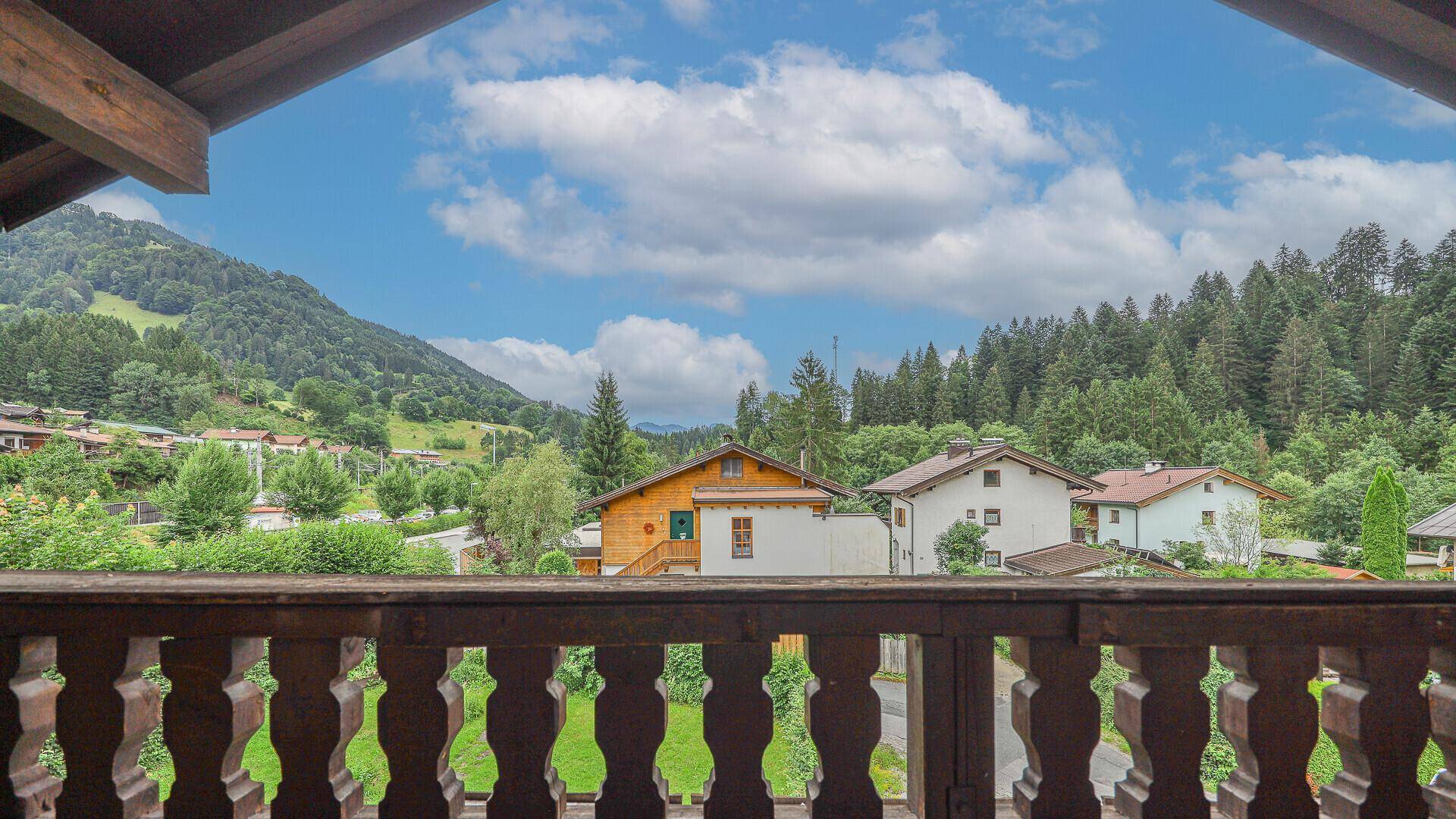 Panoramablick vom Balkon auf die umliegende Berglandschaft und Häuser.