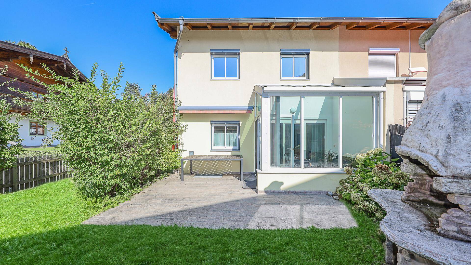 Gepflasterte Terrasse neben dem Wintergarten, ideal für Mahlzeiten im Freien.