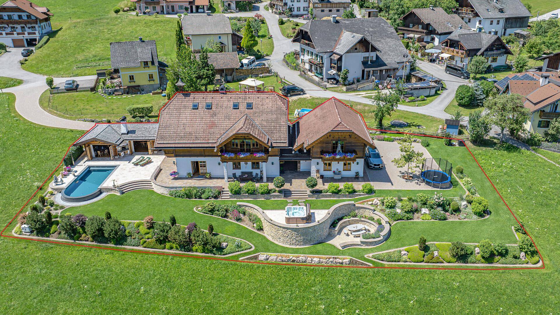 Luftaufnahme eines luxuriösen Anwesens mit Pool, Whirlpool und gepflegtem Gartenbereich.
