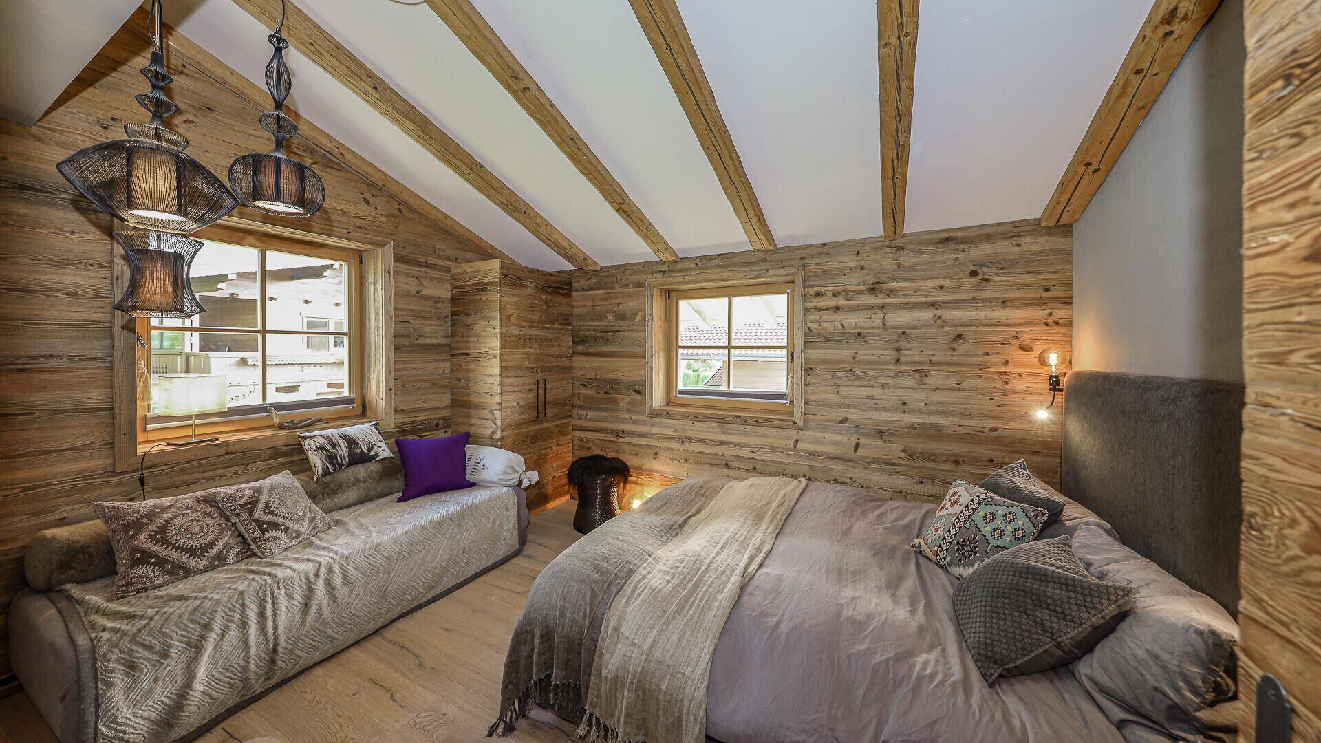 Gemütliches Schlafzimmer mit Holzwänden, Dachschrägen und bequemen Betten.