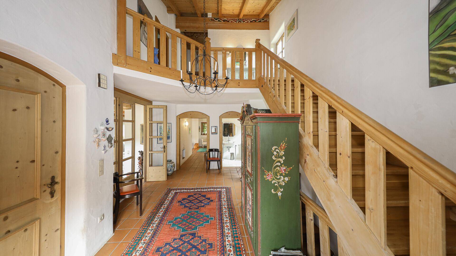 Geräumiger Flur mit Holztreppe, Terrakottafliesen und Holzbalkendecke.