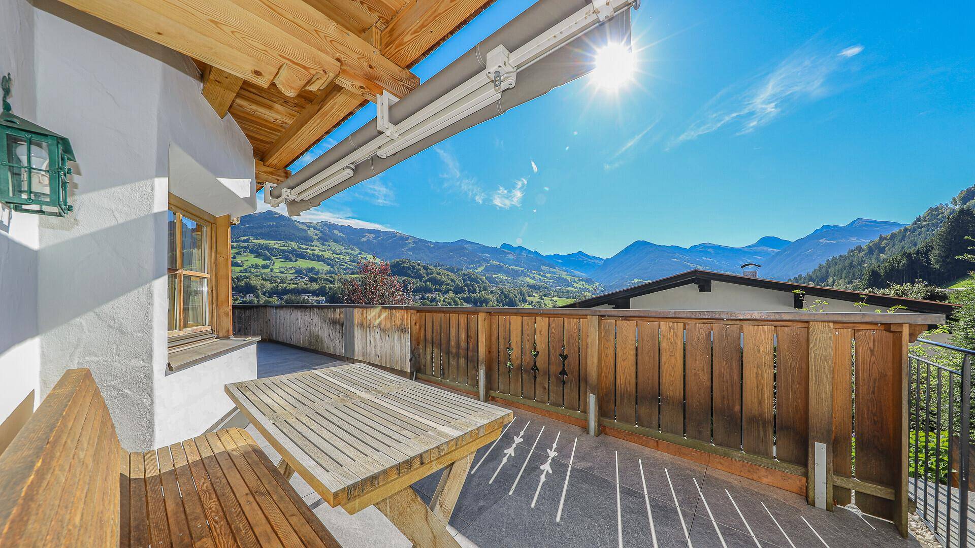 Gemütlicher Holzbalkon mit Sitzgelegenheiten und herrlichem Panoramablick auf die Berge.