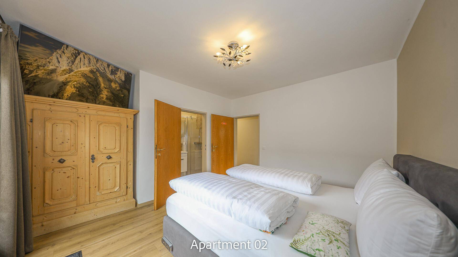 Schlafzimmer von Apartment 02 mit traditionellem Holzschrank und einer Wandmalerei mit Bergmotiv.