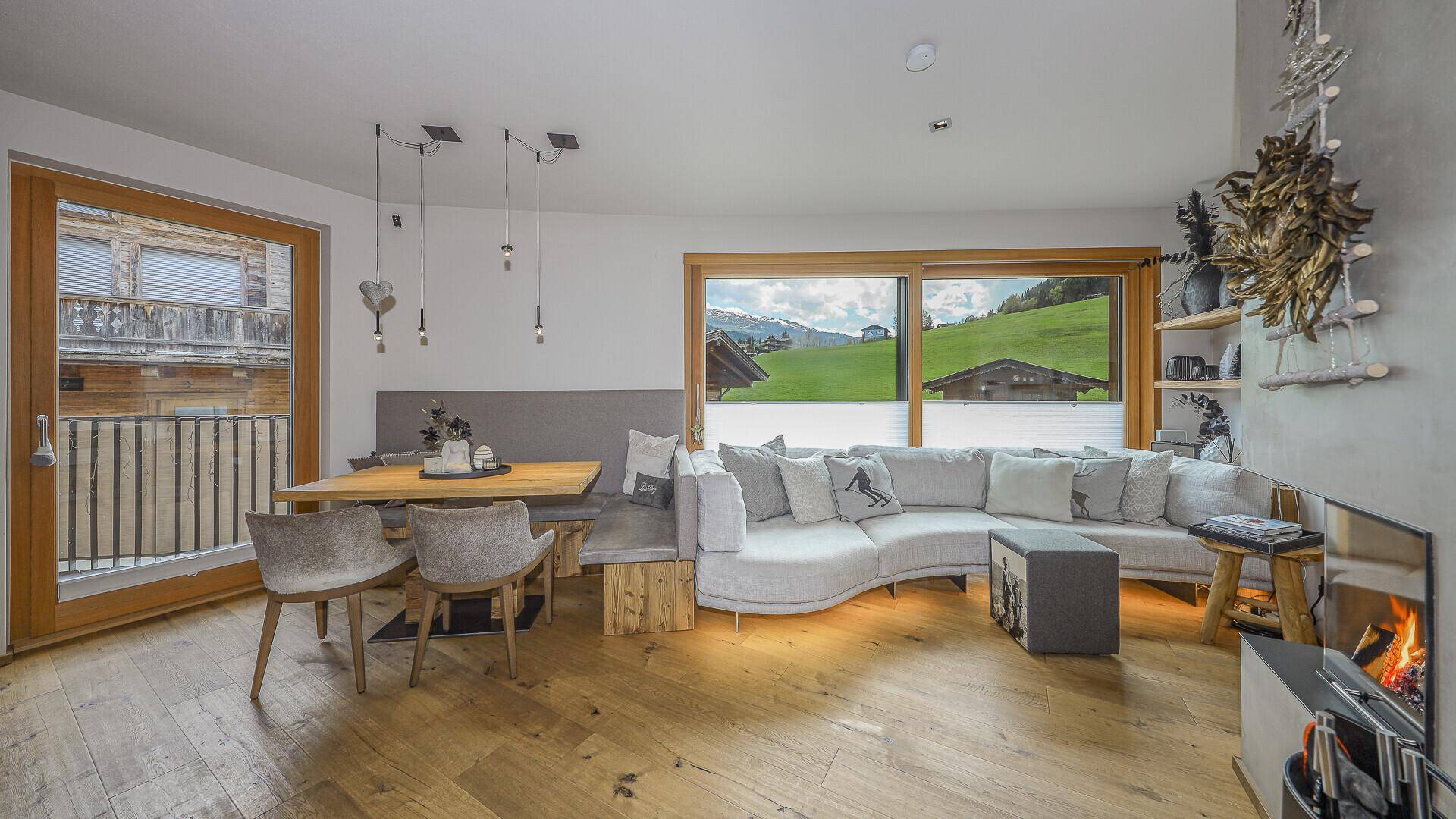 Gemütlicher Wohnbereich mit großem Sofa, Kamin und Zugang zum Balkon.