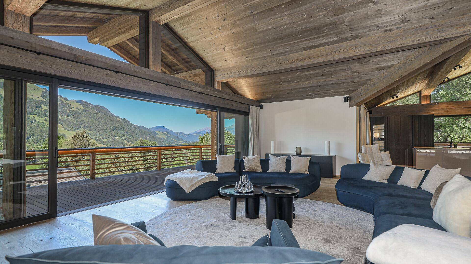 Helles Wohnzimmer mit Zugang zu einer großen Terrasse und Panoramablick auf die Berge.