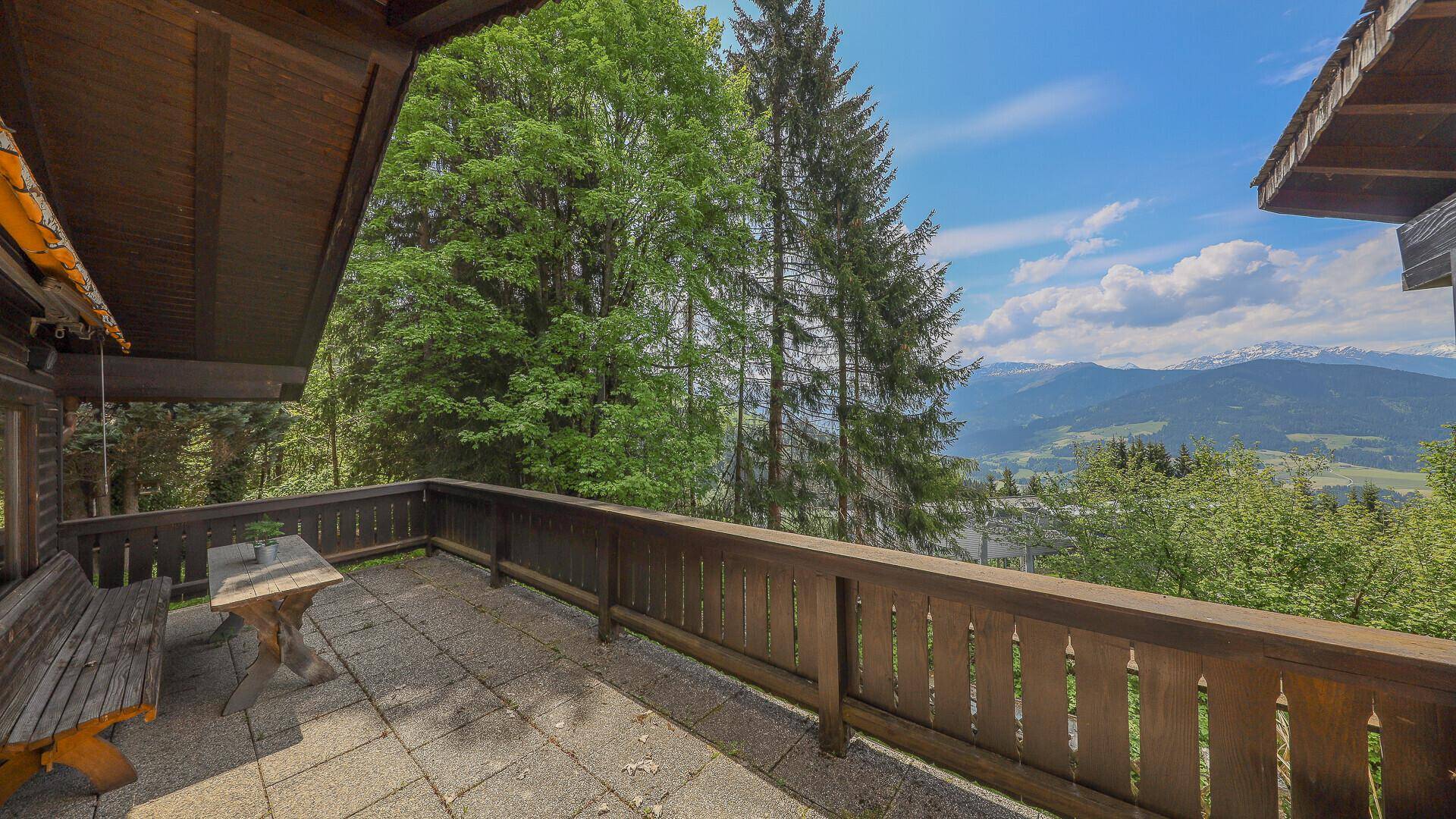 Geräumige Terrasse mit Holzbalkon und Sitzgelegenheiten, bietet einen weiten Bergblick.