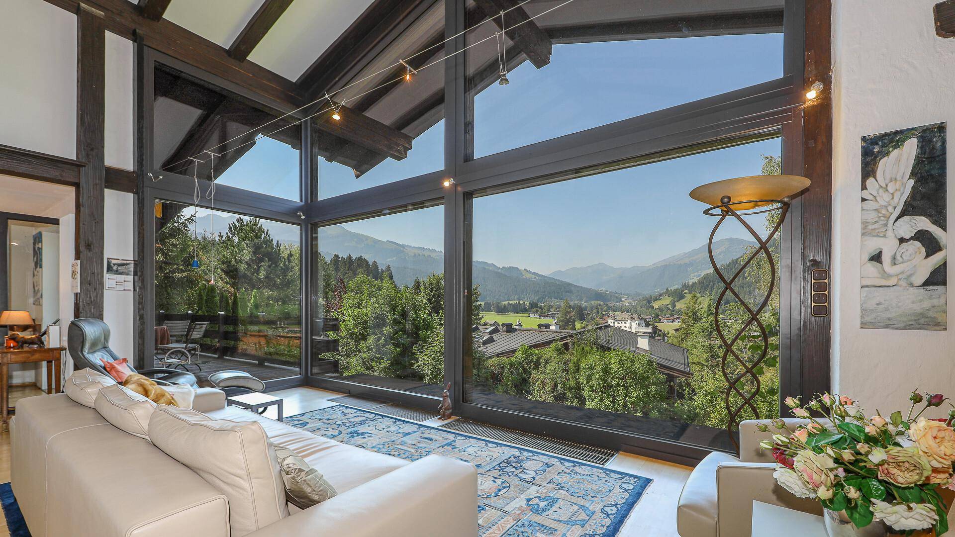Helles Wohnzimmer mit raumhohen Fenstern, die einen atemberaubenden Blick auf die Berge bieten.